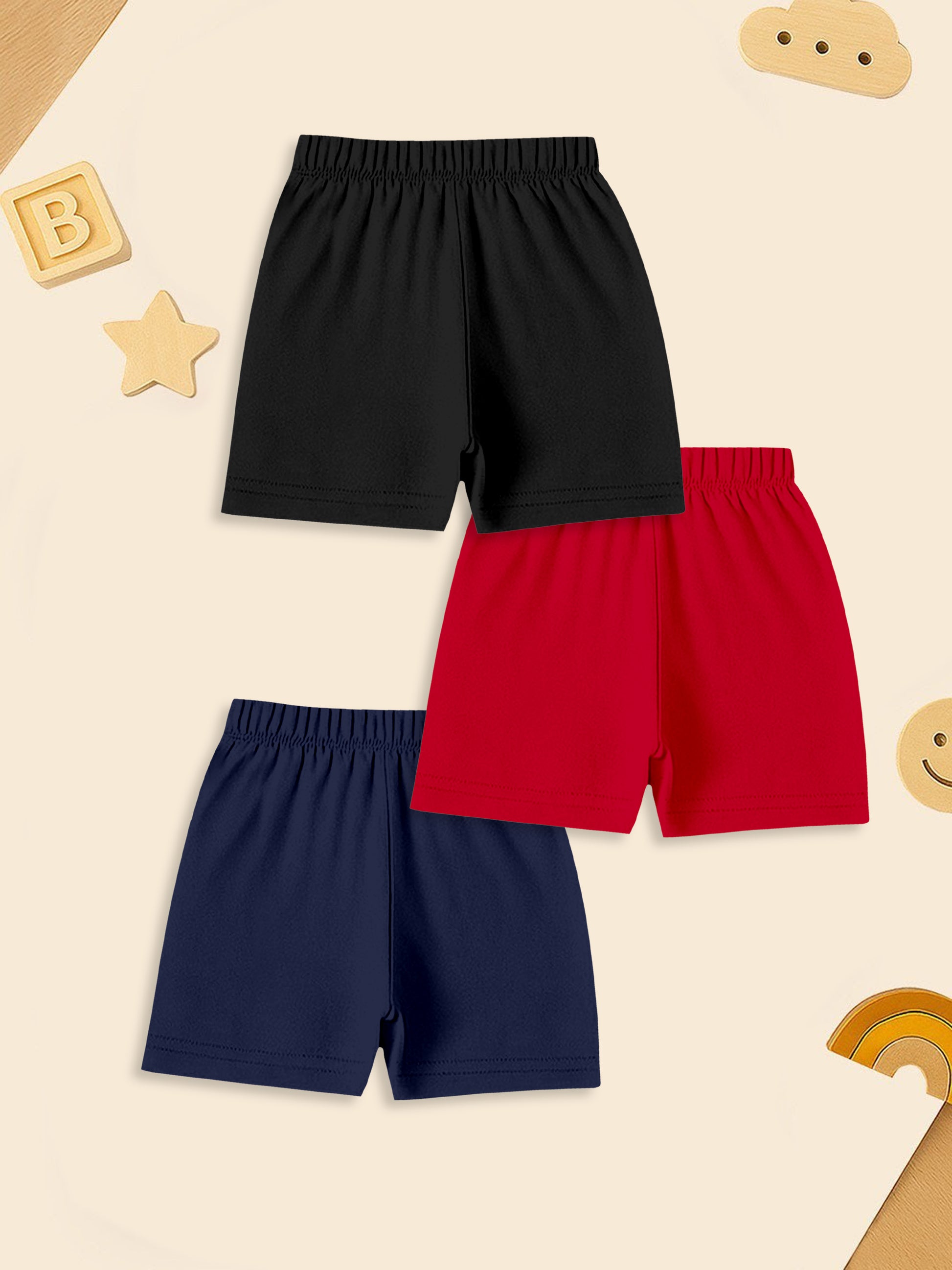 Three pairs of kids' shorts in black, red, and navy on a playful beige background