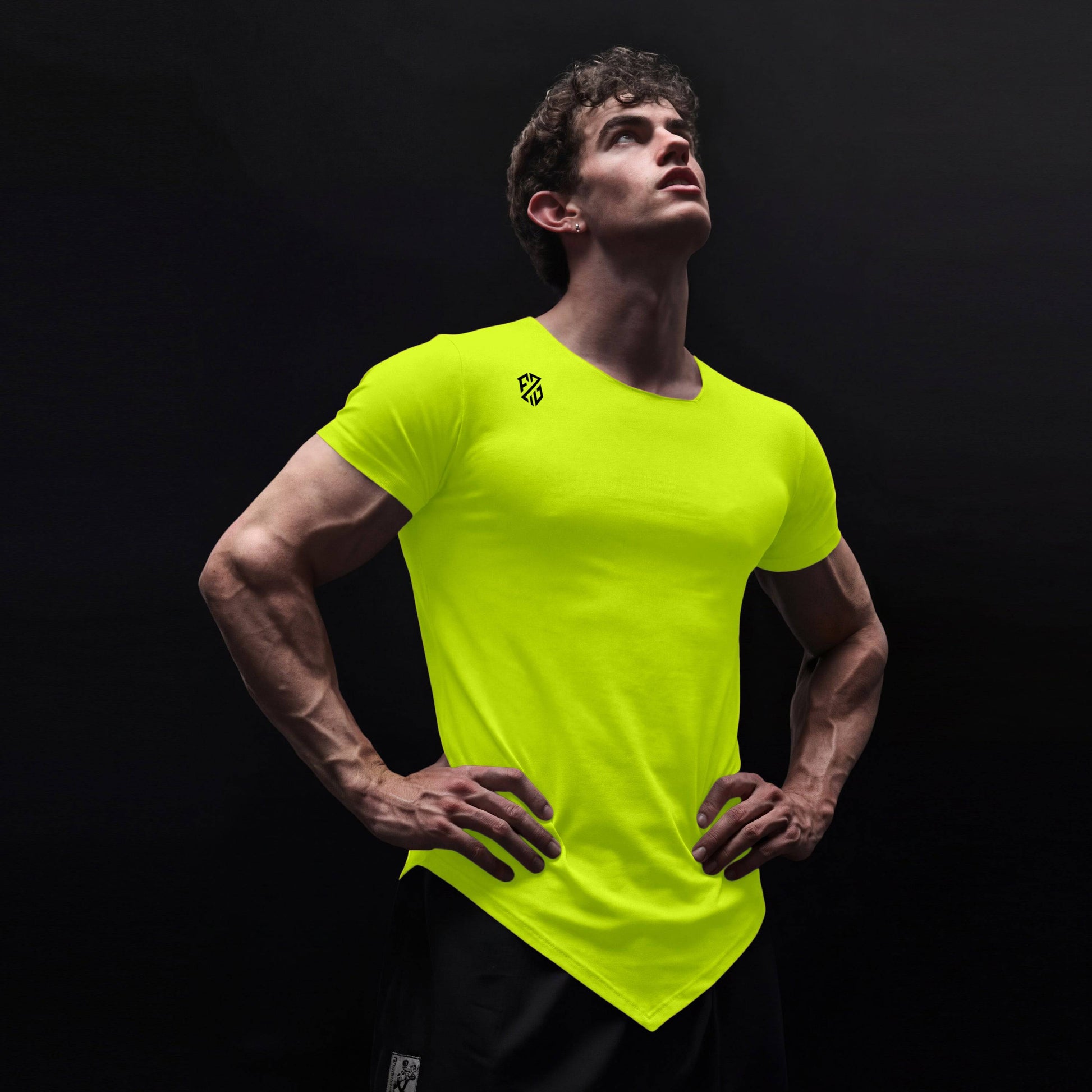 Man wearing bright yellow fitted athletic t-shirt with logo, posing against black background