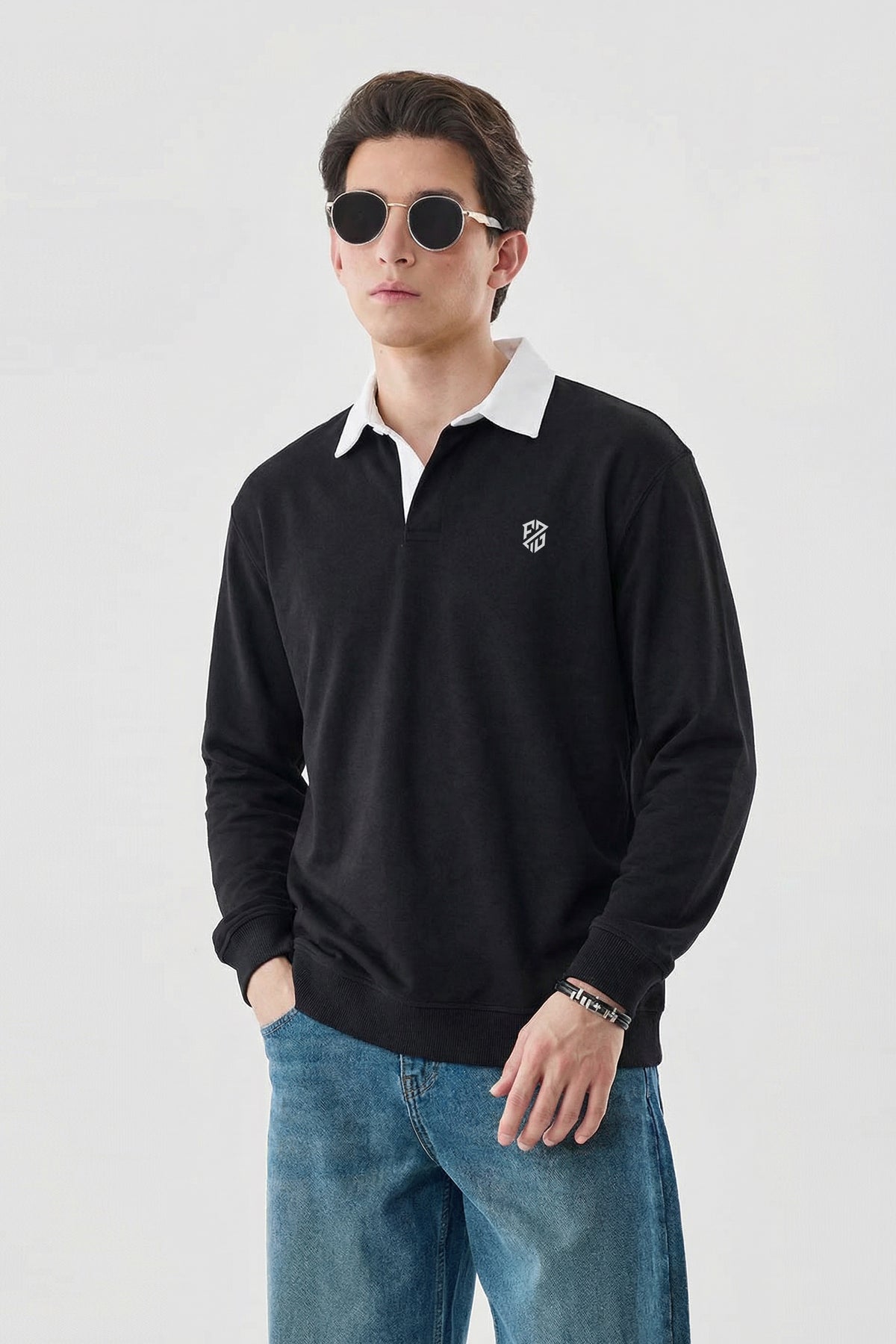 Man wearing black long sleeve rugby shirt with white collar, round sunglasses, and blue jeans
