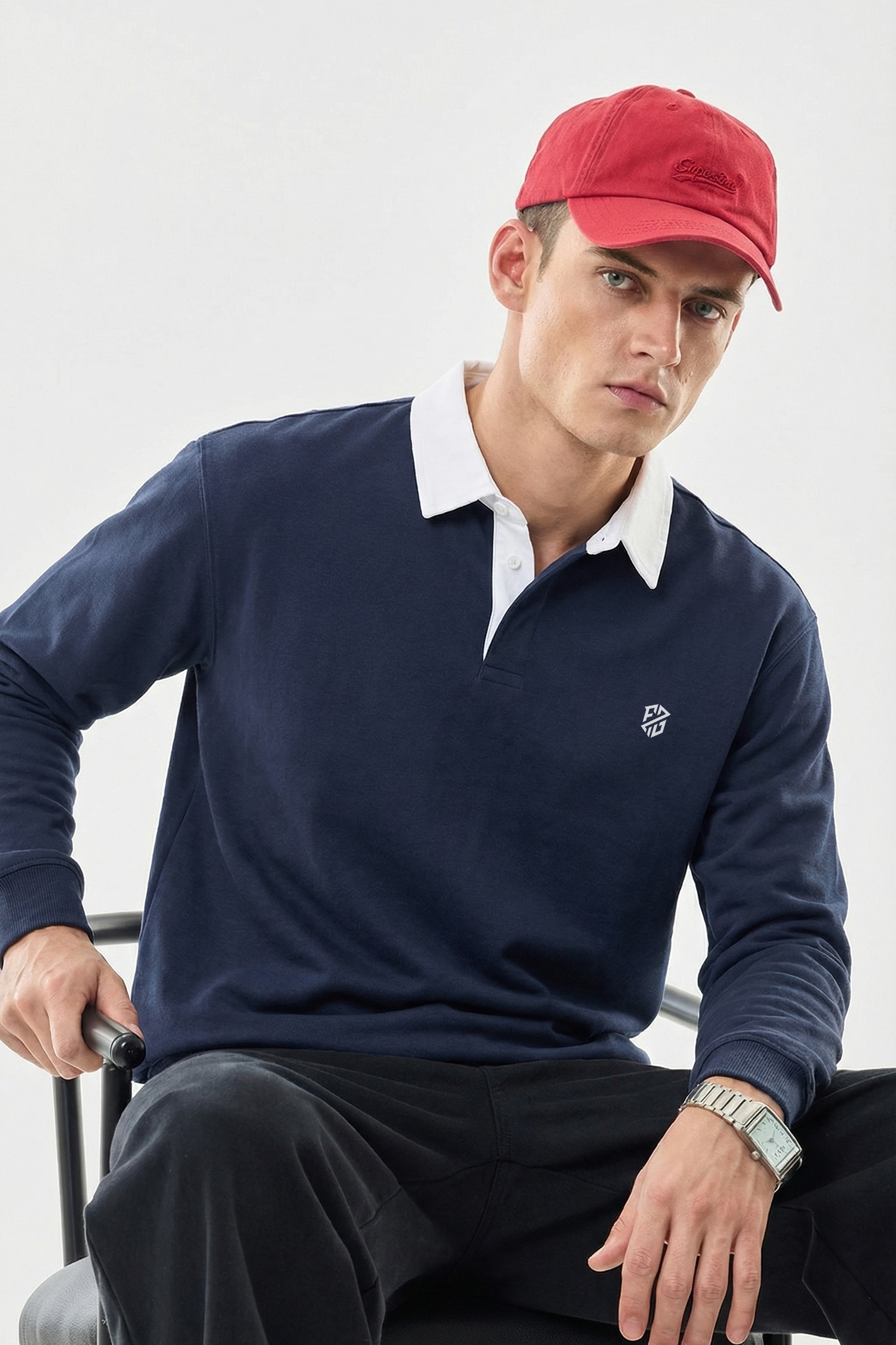 Man in navy rugby shirt with white collar and red cap, sitting on a chair
