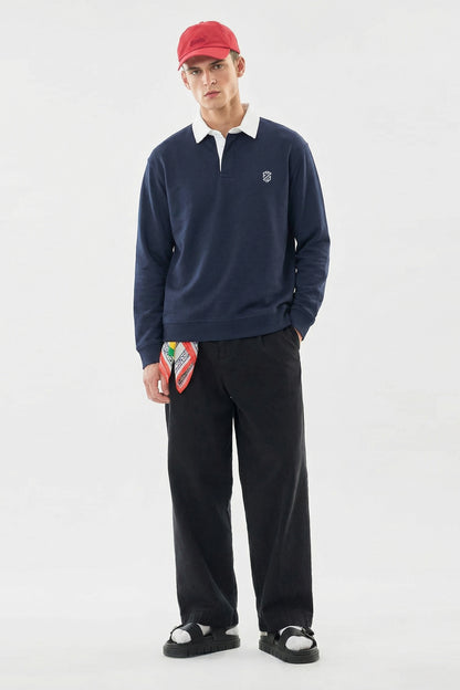 Man in navy long-sleeve rugby shirt, white collar, red cap, black pants, and sandals