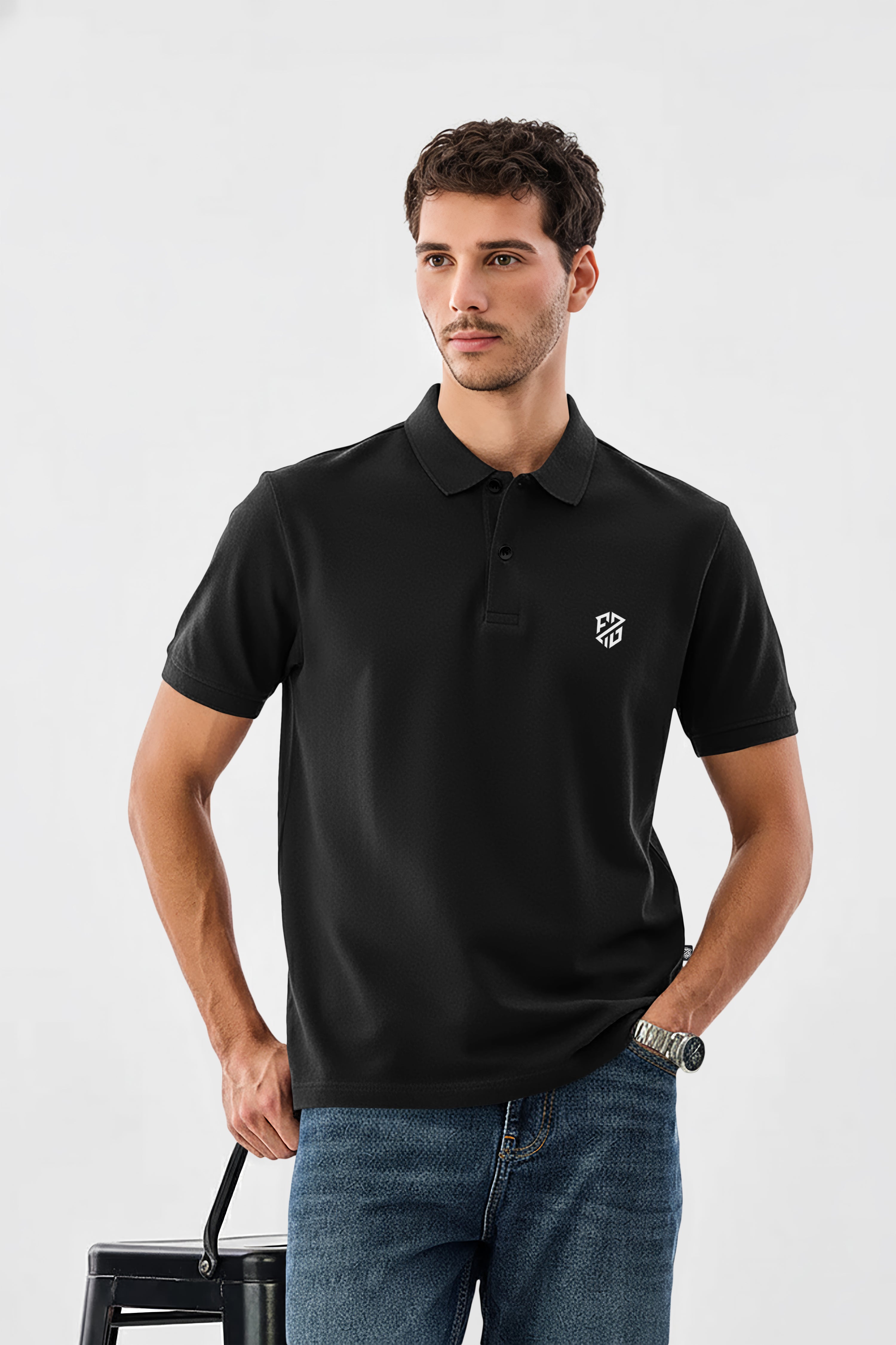 Man in black short sleeve polo shirt with white geometric chest logo and blue jeans