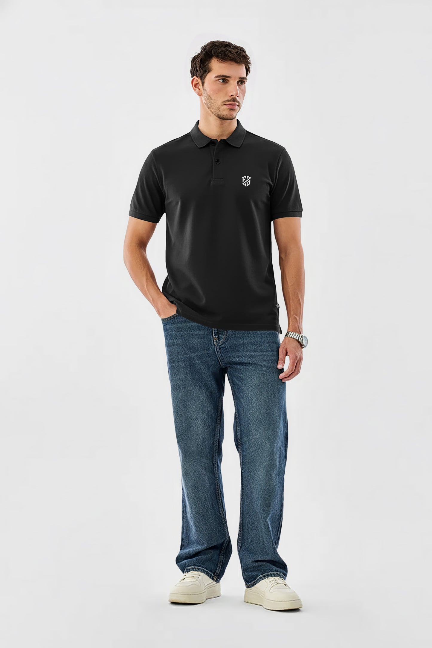 Man wearing black polo shirt with logo, blue jeans, and white sneakers on white background