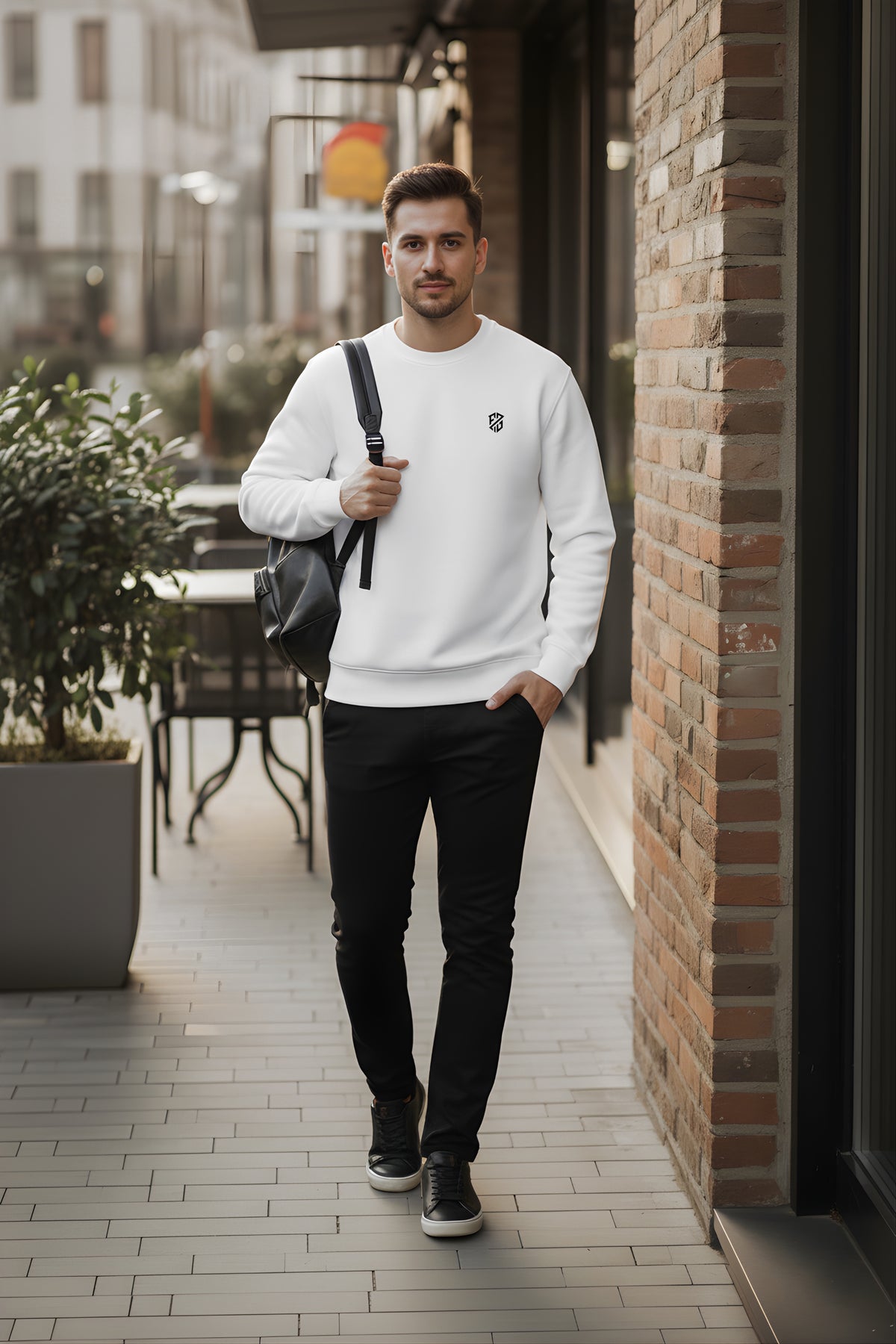 Man in a white sweatshirt and black pants with a backpack walking outdoors