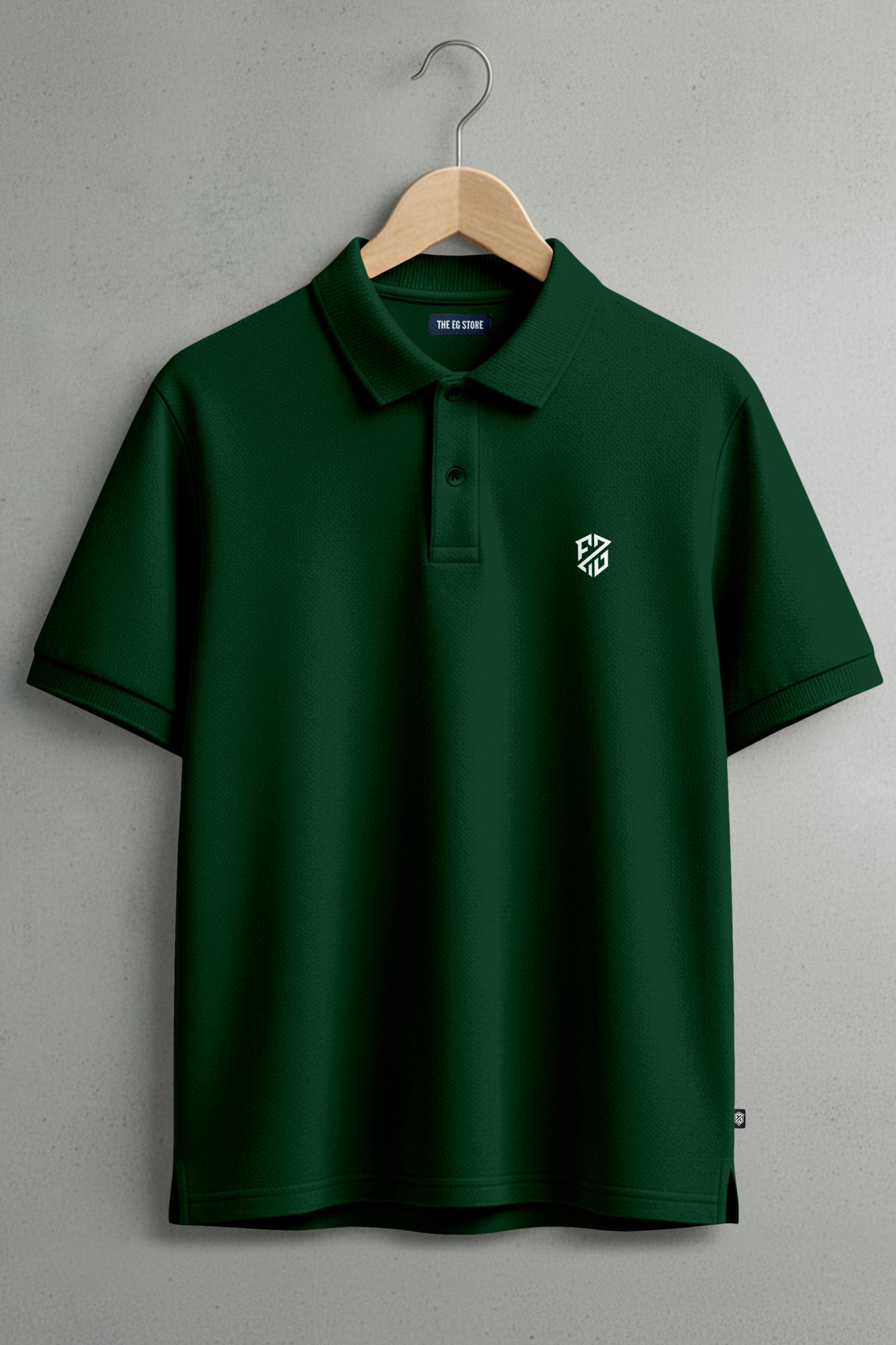 Dark green polo shirt with embroidered white chest logo, hanging on a wooden hanger.