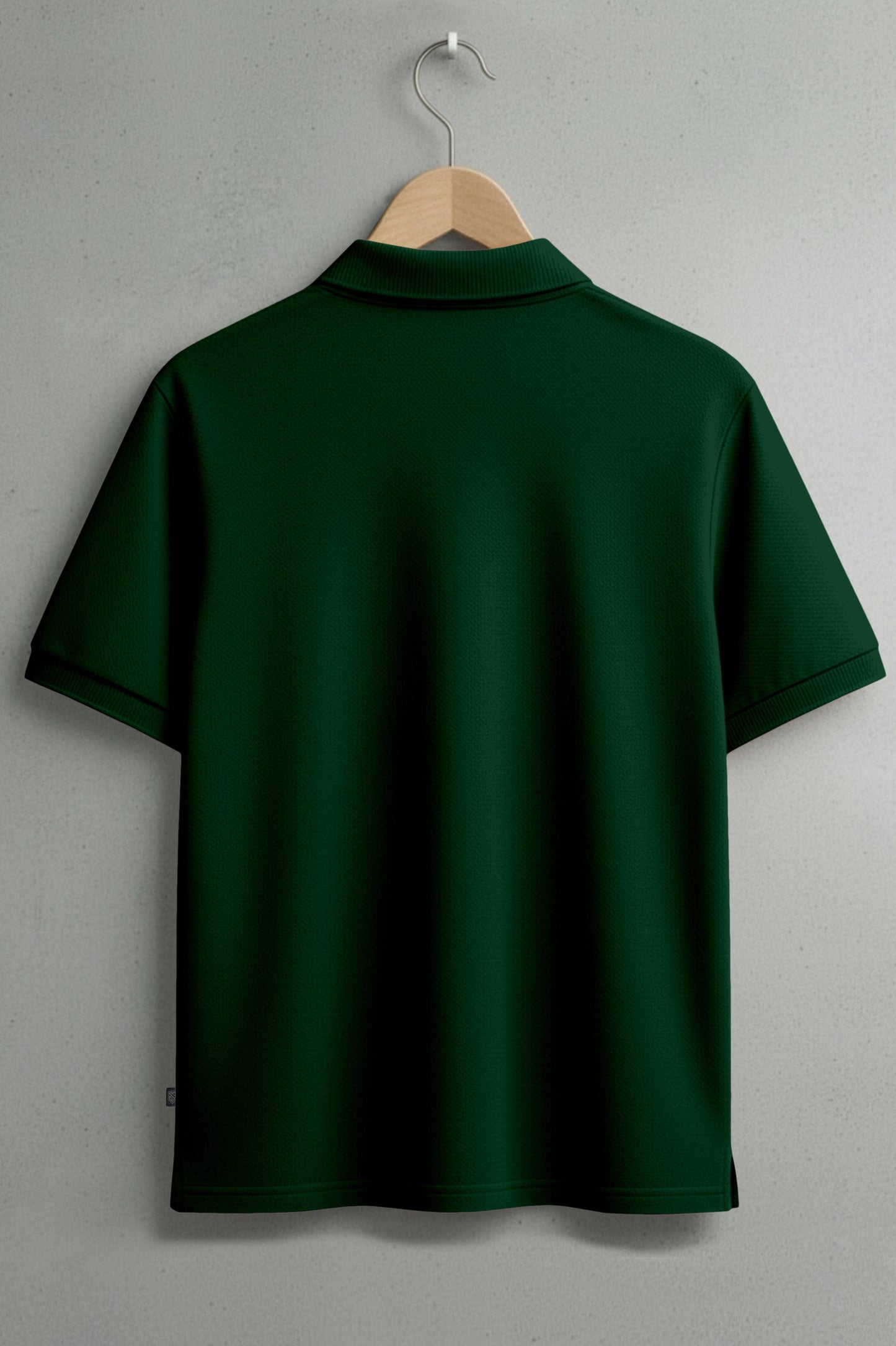 back view of dark green short sleeve polo shirt on a hanger against a plain wall