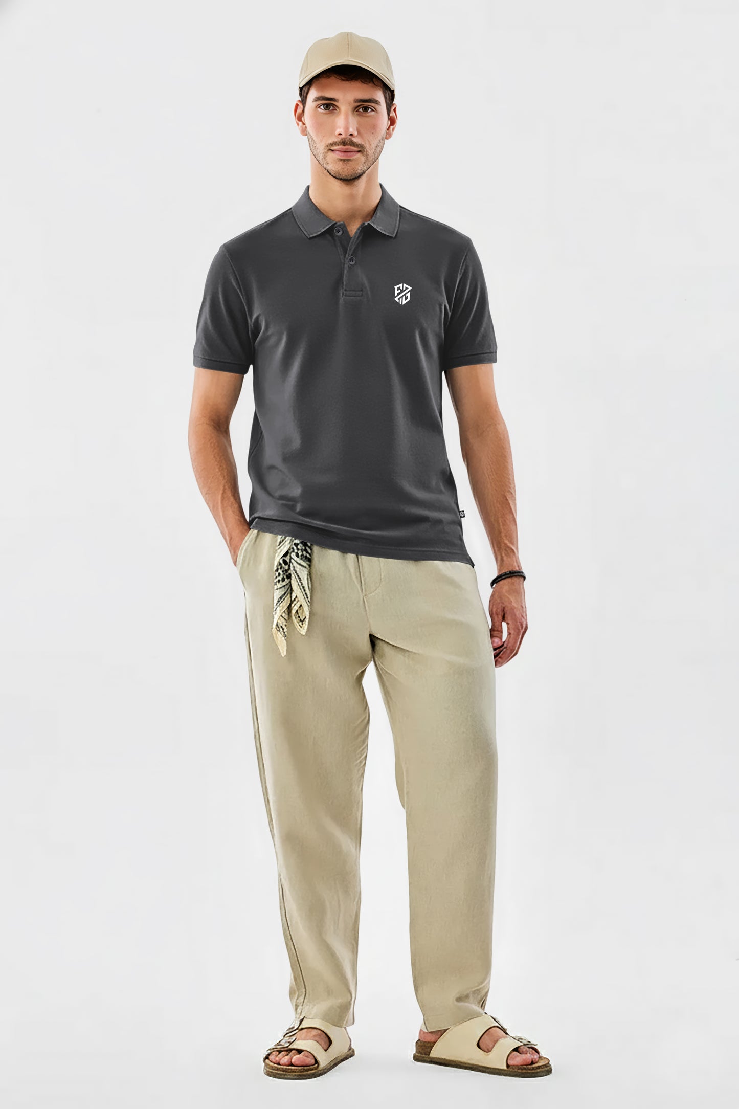 Man in dark polo shirt with logo, beige pants, cap, and sandals, casual outfit