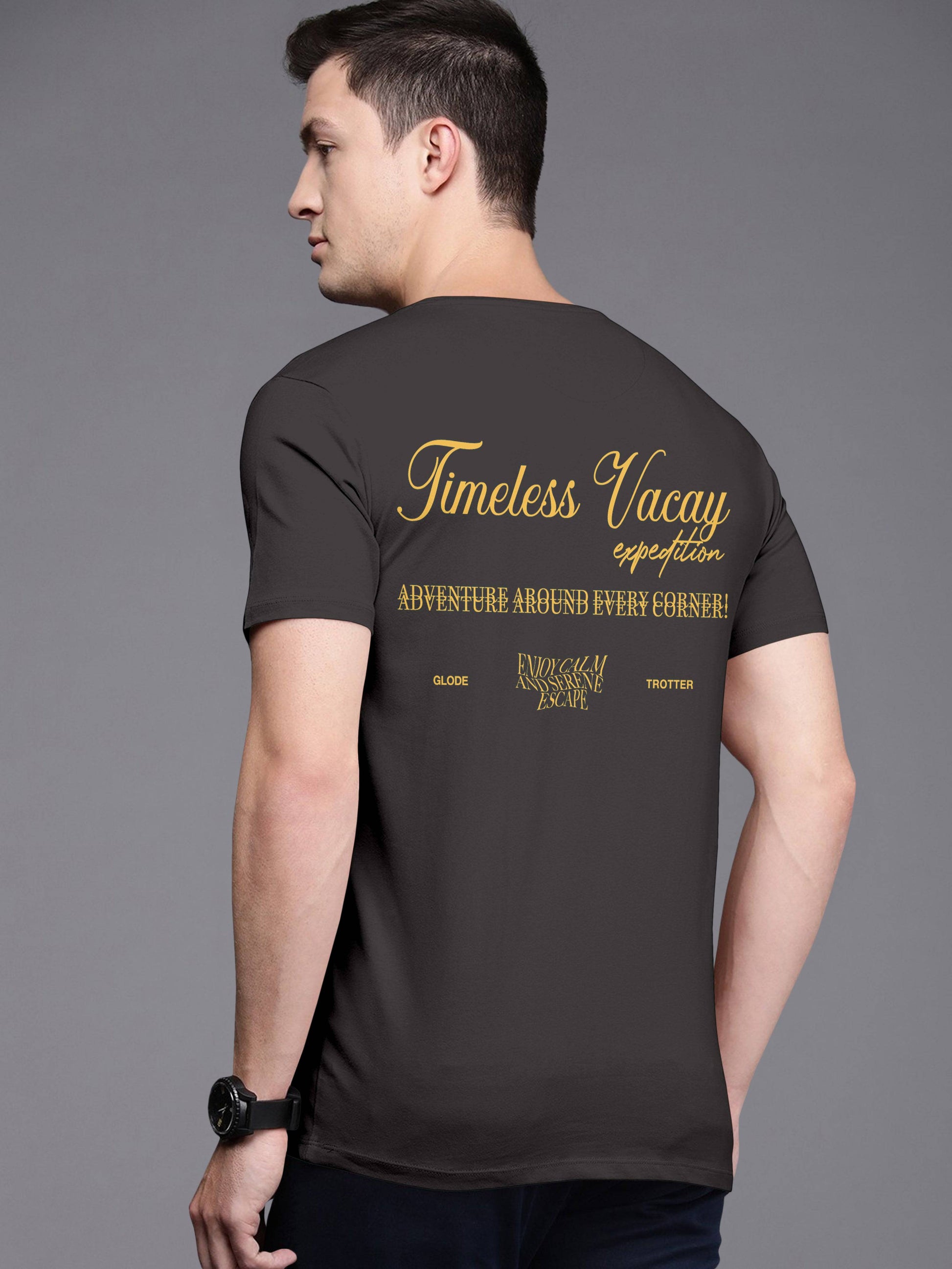 Man wearing black t-shirt with gold 'Timeless Vacay expedition' travel graphic on back