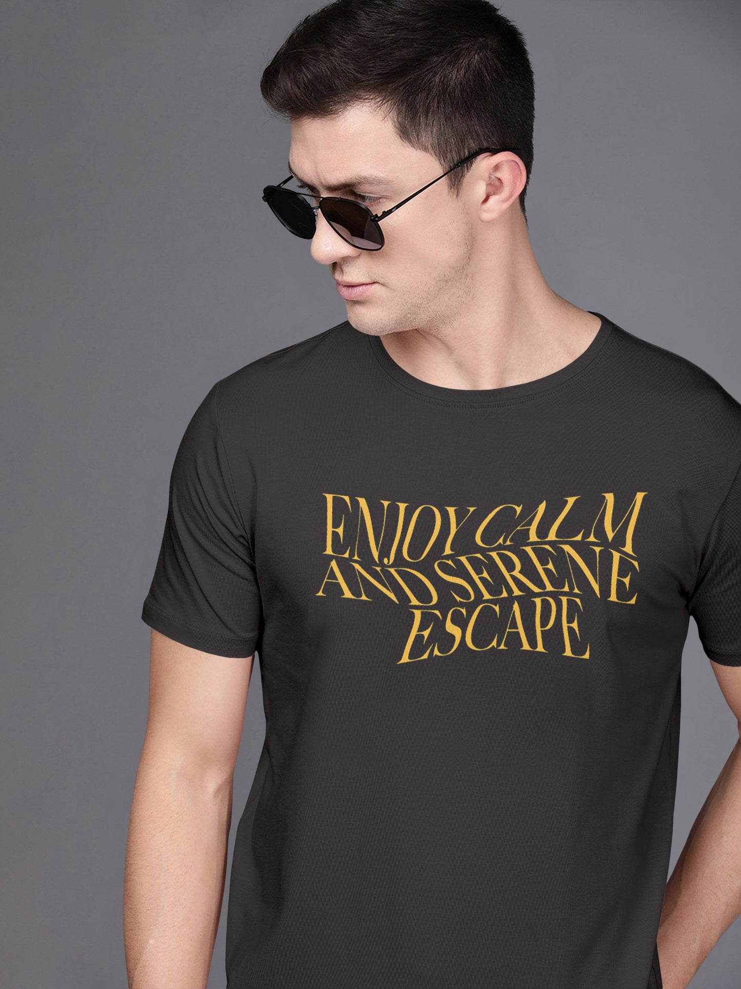 Man in sunglasses wearing a black t-shirt with yellow text 'Enjoy Calm and Serene Escape'.