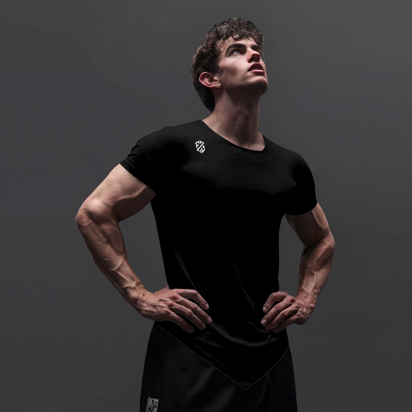 Athletic man wearing a fitted black workout t-shirt and shorts on a dark background