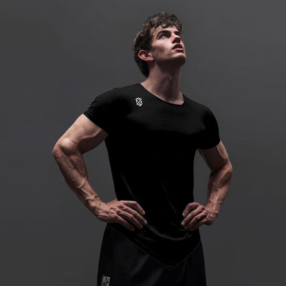 Athletic man wearing a fitted black workout t-shirt and shorts on a dark background