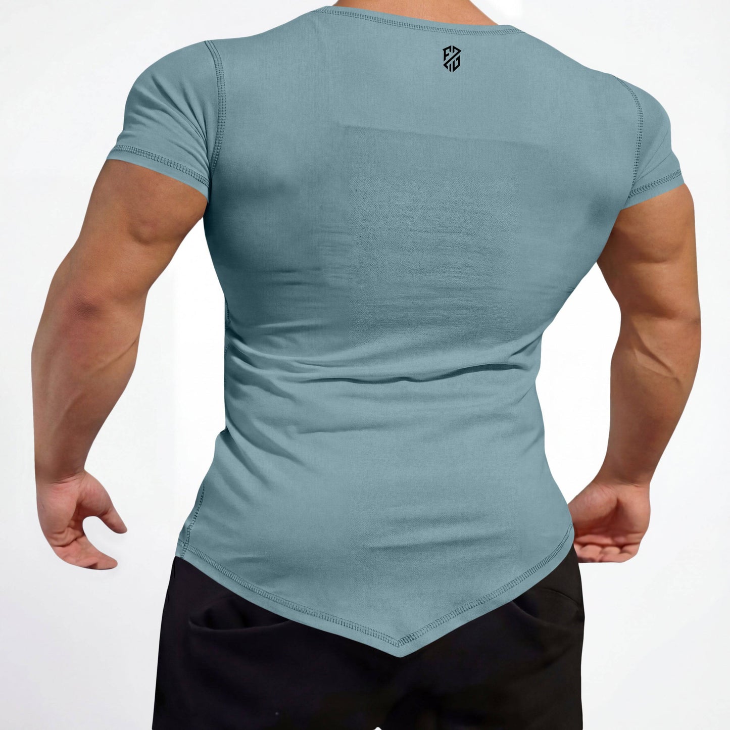 Athletic man wearing a fitted light blue short sleeve t-shirt with angled hem and black pants