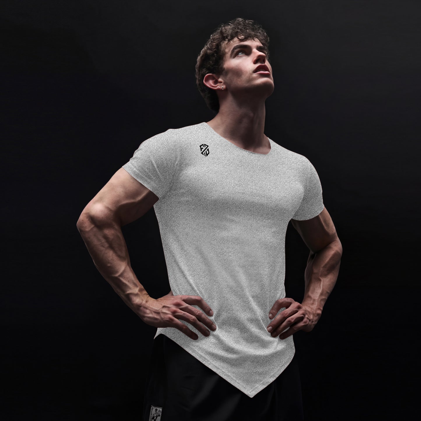 Athletic man in white fitted t-shirt with logo and black shorts against dark background