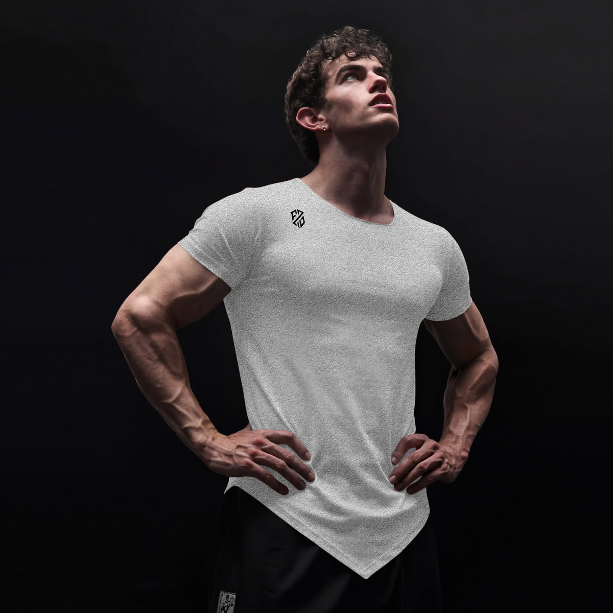 Athletic man in white fitted t-shirt with logo and black shorts against dark background