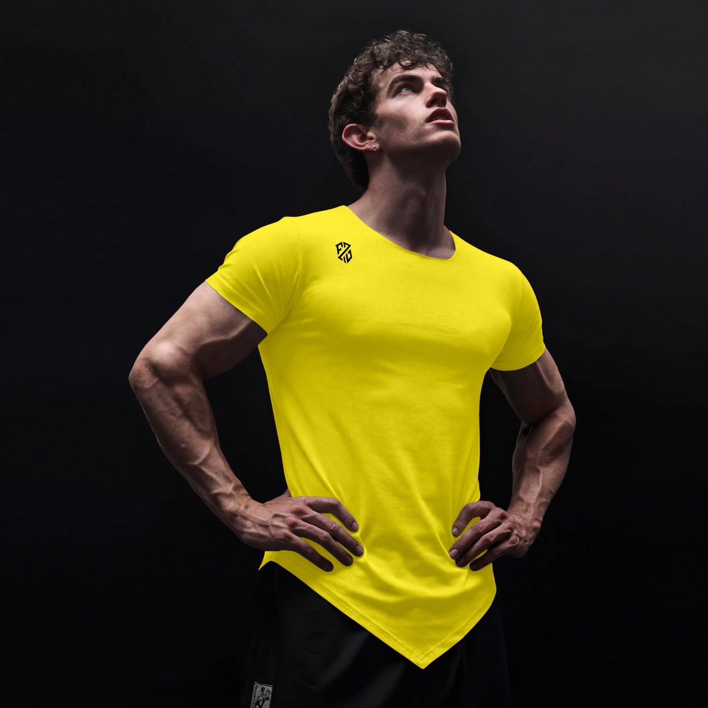 Man wearing vibrant yellow athletic t-shirt with angled hem, fitness apparel on black background