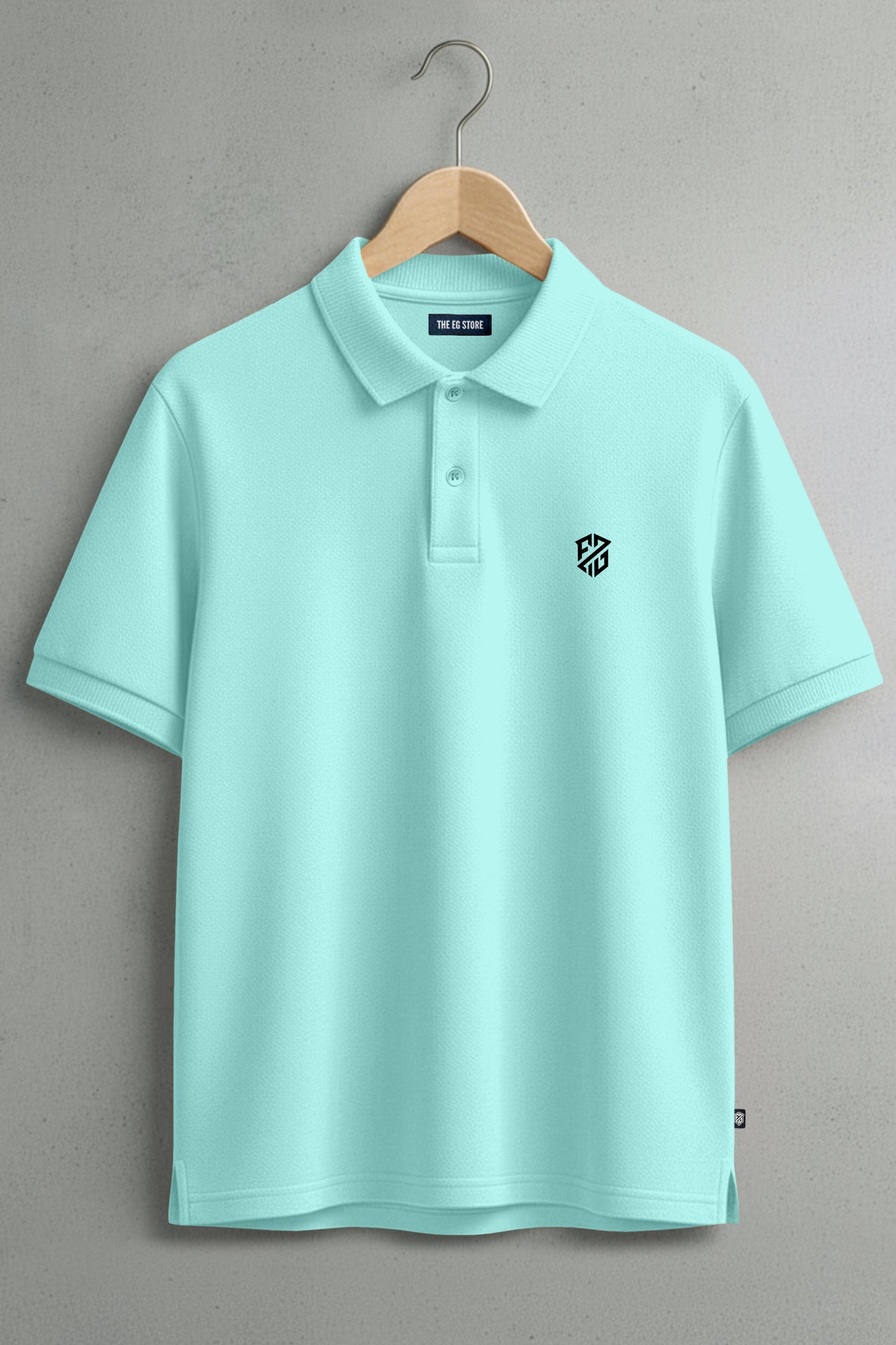 Light blue polo shirt with short sleeves and a black geometric logo on the chest, hanging on a wooden hanger.