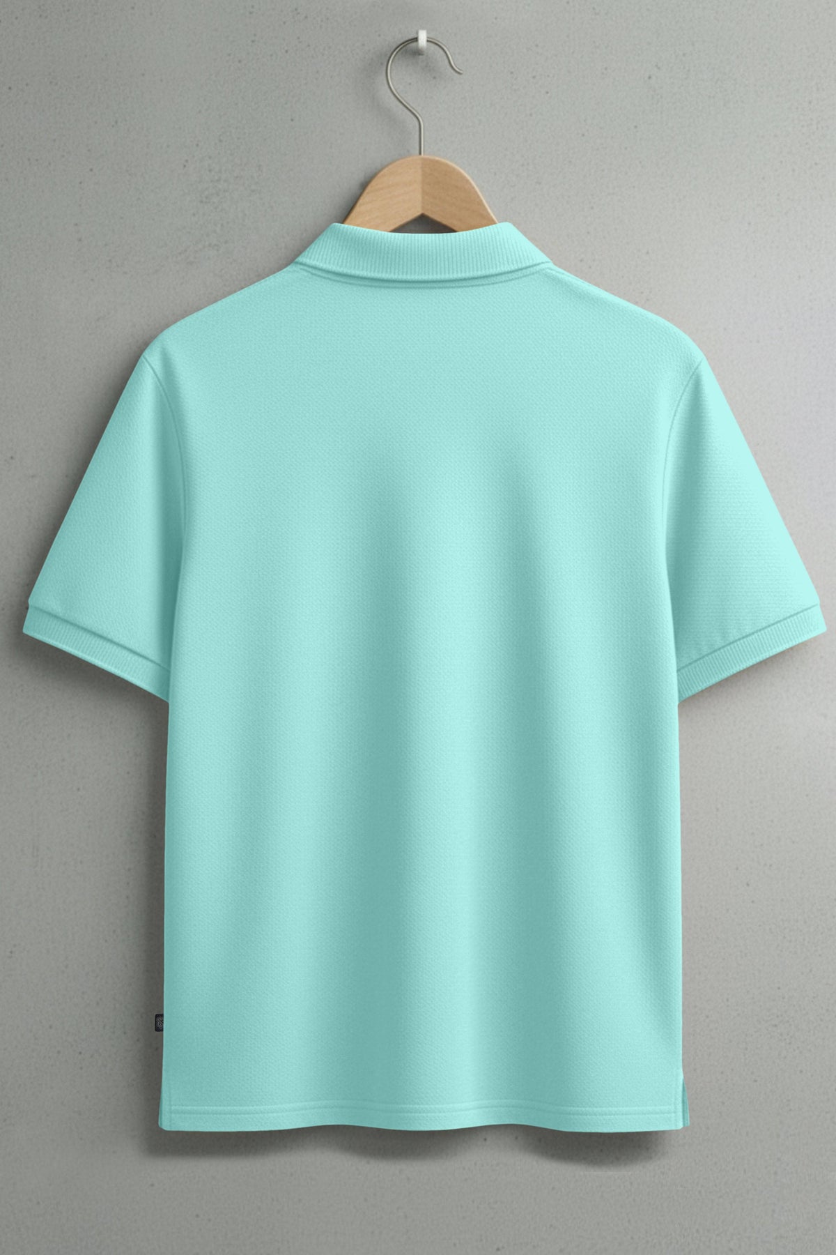 Light blue short sleeve polo shirt on hanger against gray wall, back view