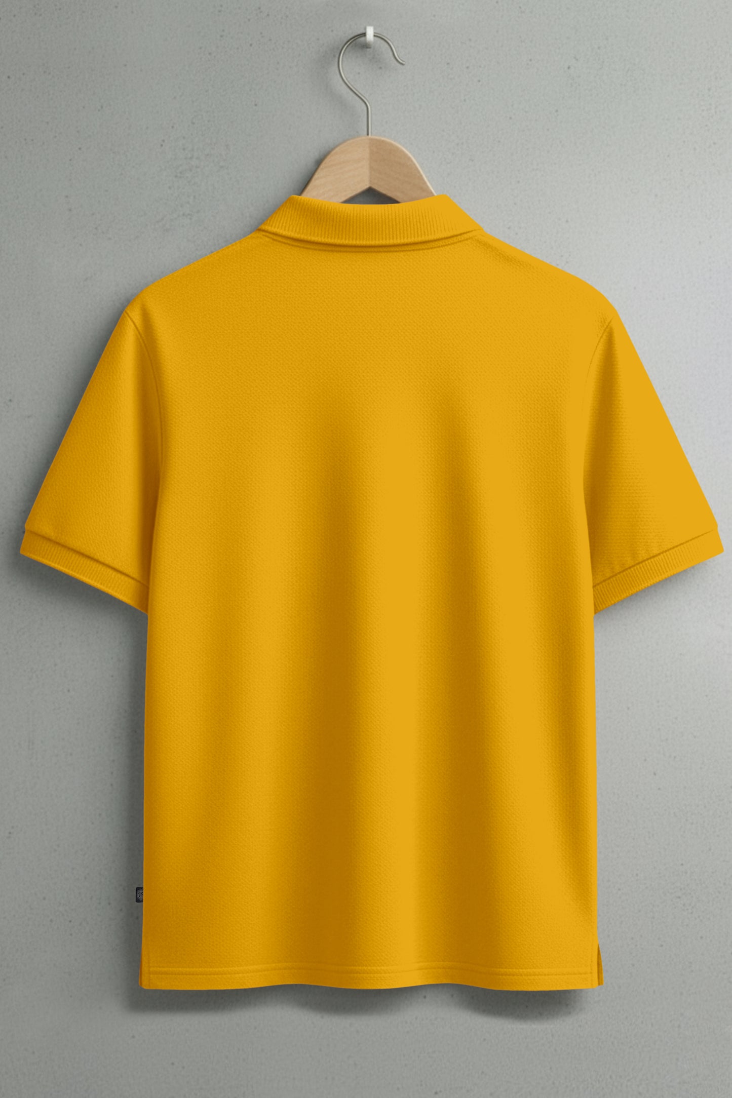 Back view of yellow short-sleeve polo shirt on wooden hanger against gray wall