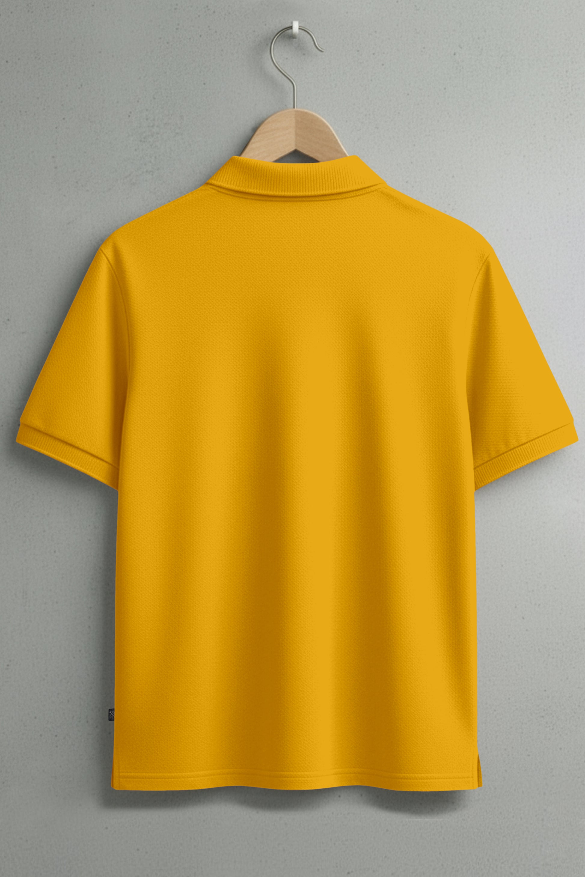 Back view of yellow short-sleeve polo shirt on wooden hanger against gray wall