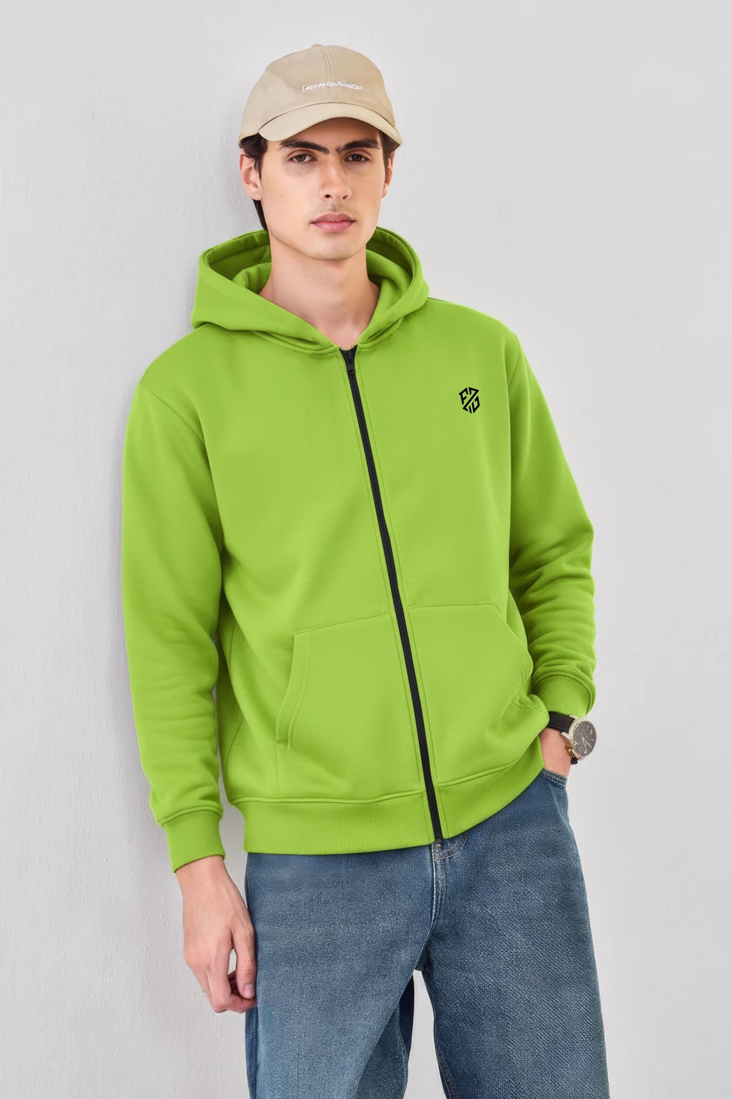 Man wearing lime green zip-up hoodie with black logo, blue jeans, and beige cap