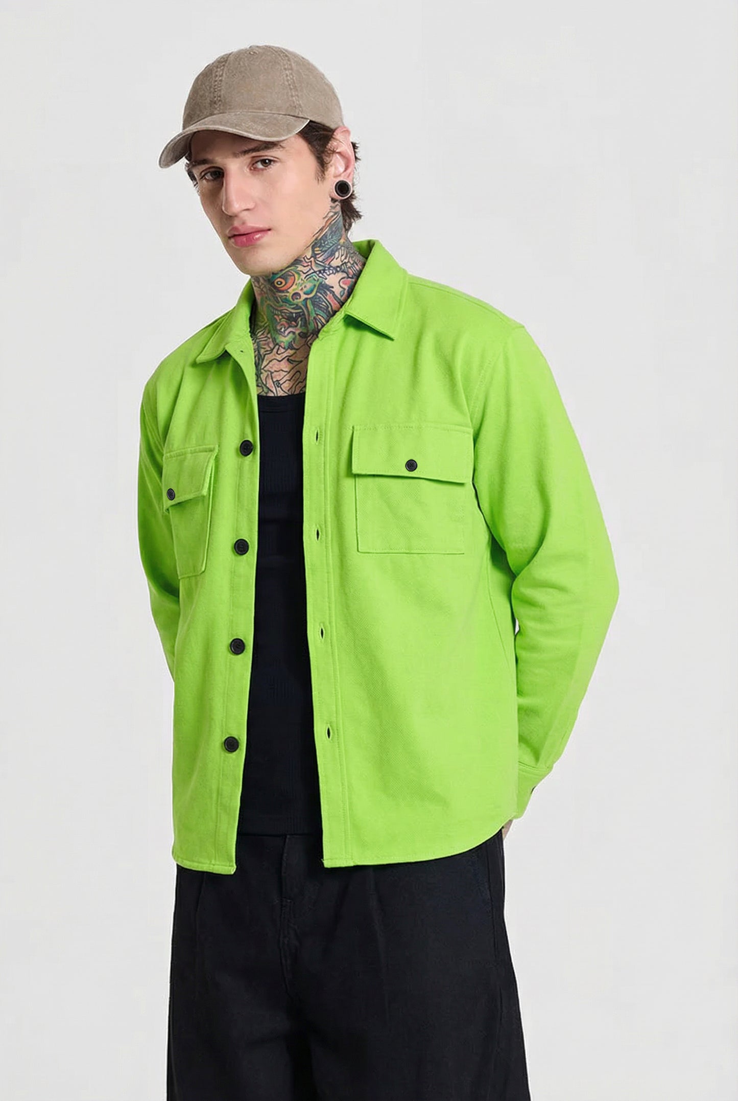 Man wearing lime green button-up shirt, beige cap, black tank top and black pants