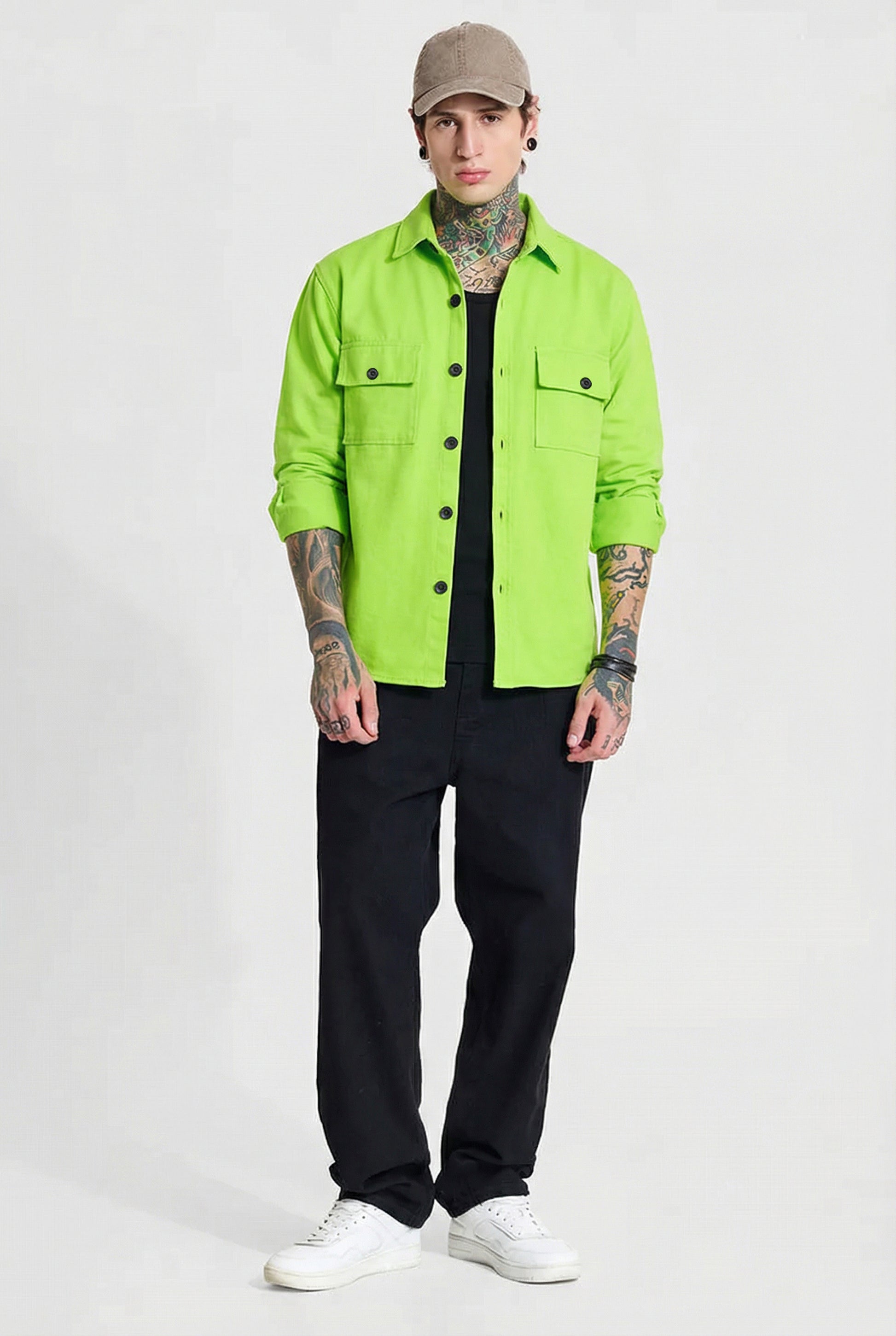 Man in neon green button-up shirt, black pants, beige cap, white sneakers, tattooed arms