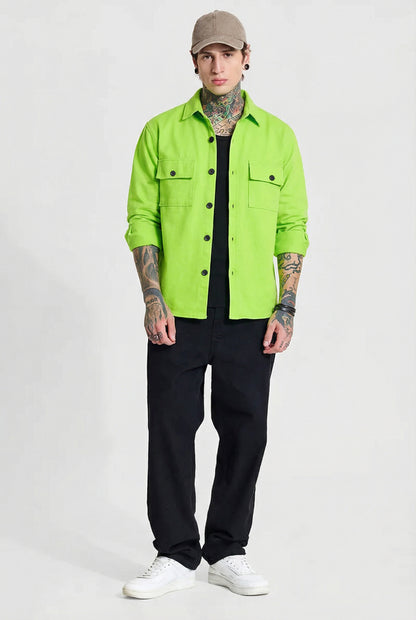 Man in neon green button-up shirt, black pants, beige cap, white sneakers, tattooed arms