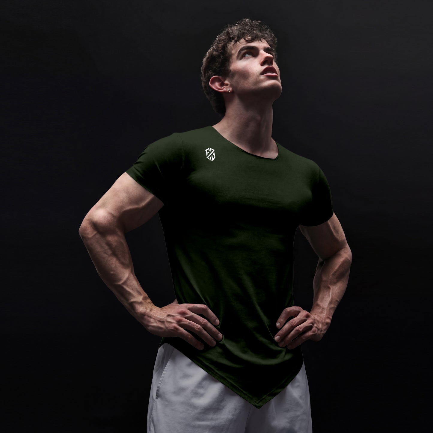 Athletic man posing in black fitted t-shirt with white logo, white shorts, black background