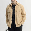 Man wearing beige button-up overshirt with front pockets, black pants, and sunglasses