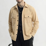 Man wearing beige button-up overshirt with front pockets, black pants, and sunglasses