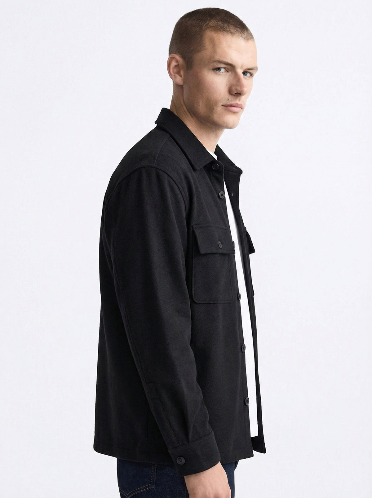 Man wearing a black button-up shirt jacket with chest pockets, side view