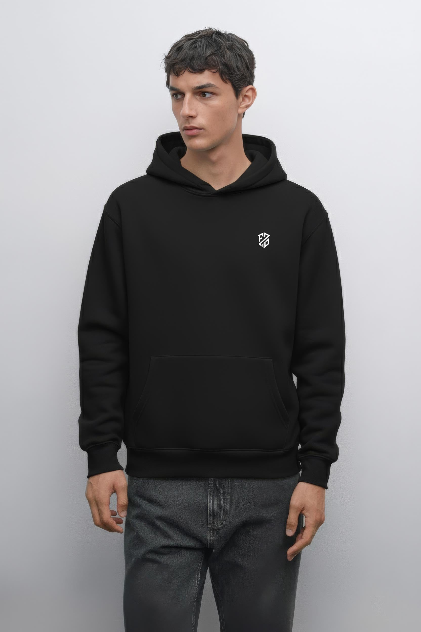 Man wearing a black hooded sweatshirt with a small white geometric logo on chest
