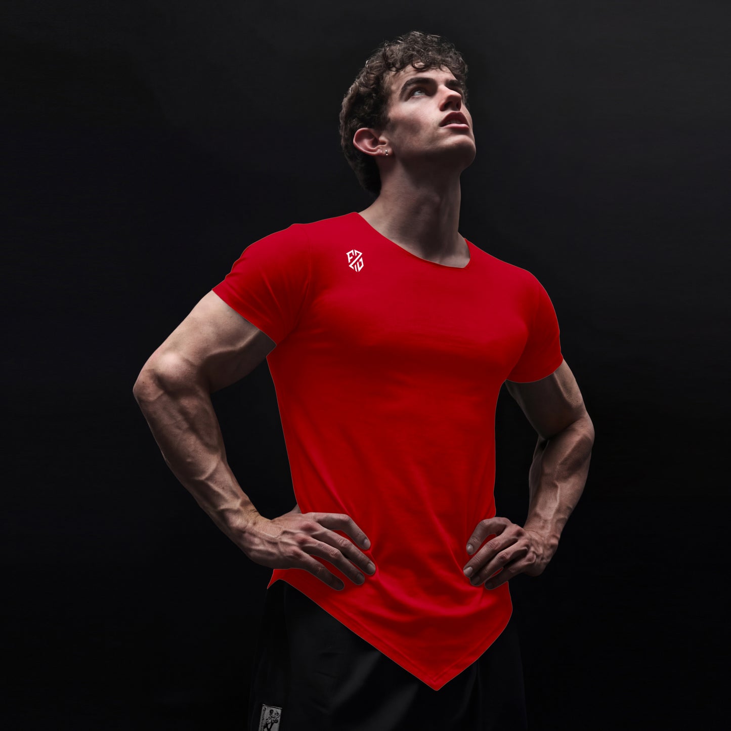 Athletic man in red fitted t-shirt with logo, posing confidently against black background