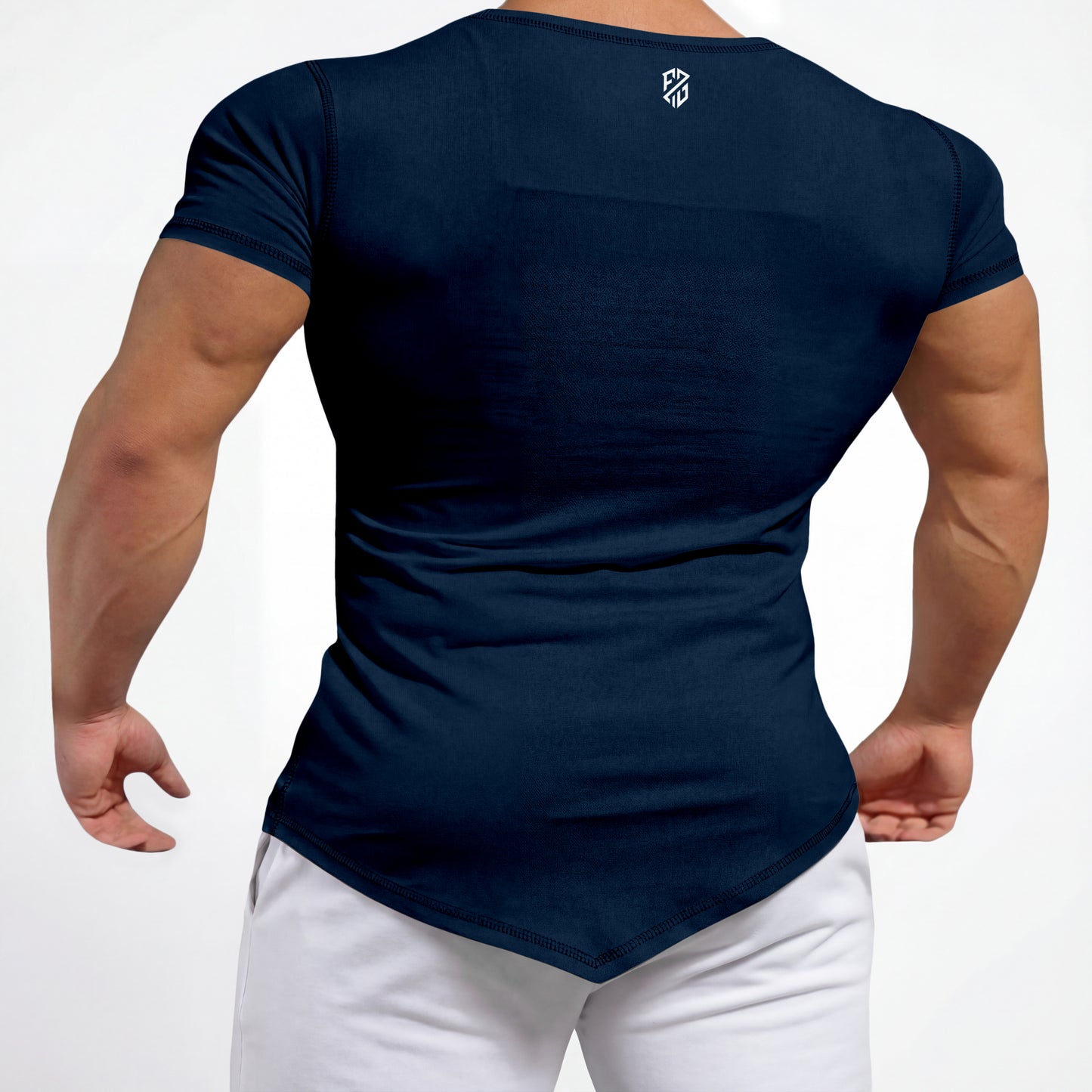 Man wearing fitted navy blue athletic t-shirt with white logo on back, white pants