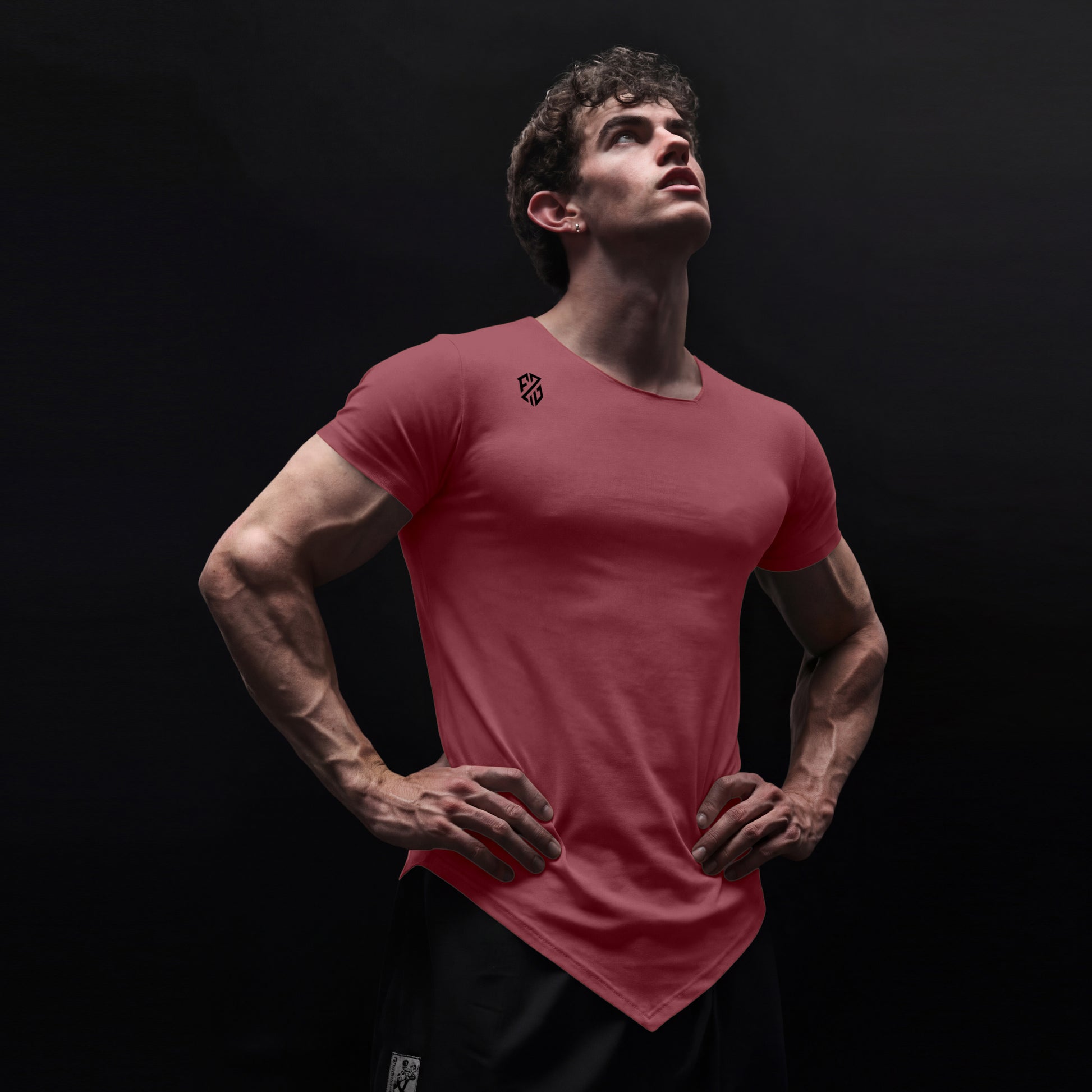 Athletic man in fitted red V-cut hem t-shirt with logo, posing against black background