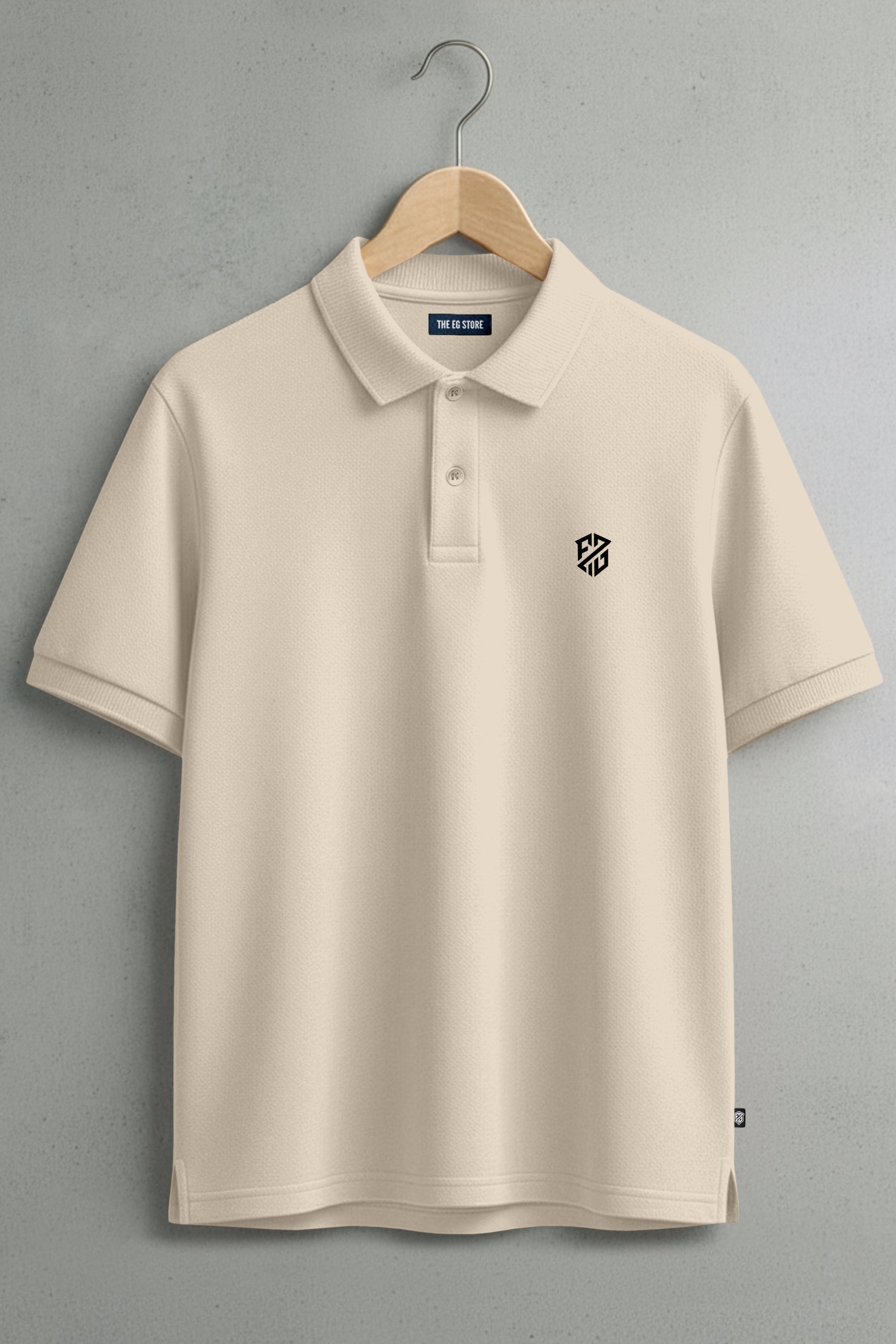 Ivory short sleeve polo shirt with black geometric logo on chest, hanging on wooden hanger