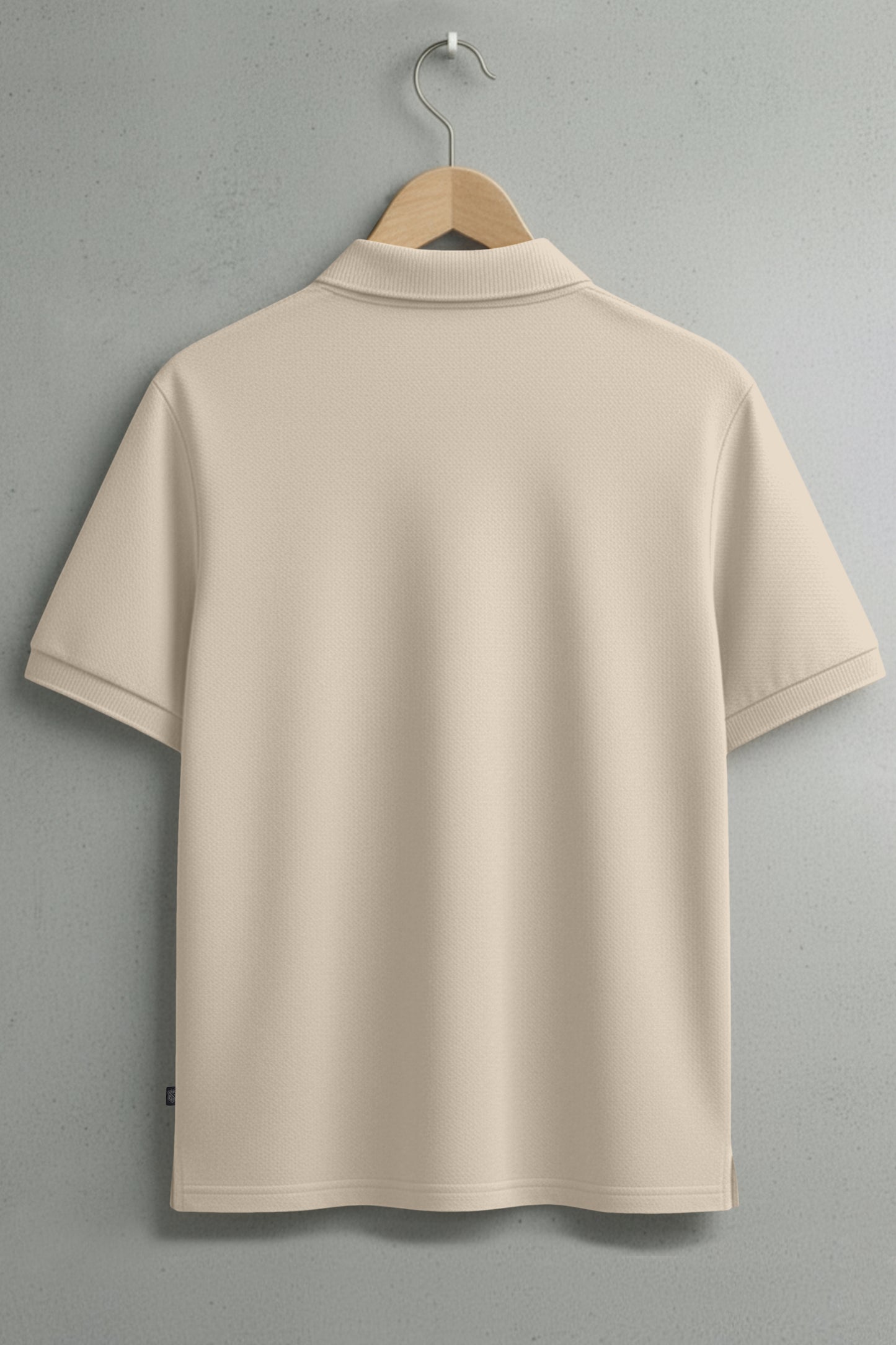 Back view of beige short-sleeve polo shirt on hanger against gray wall