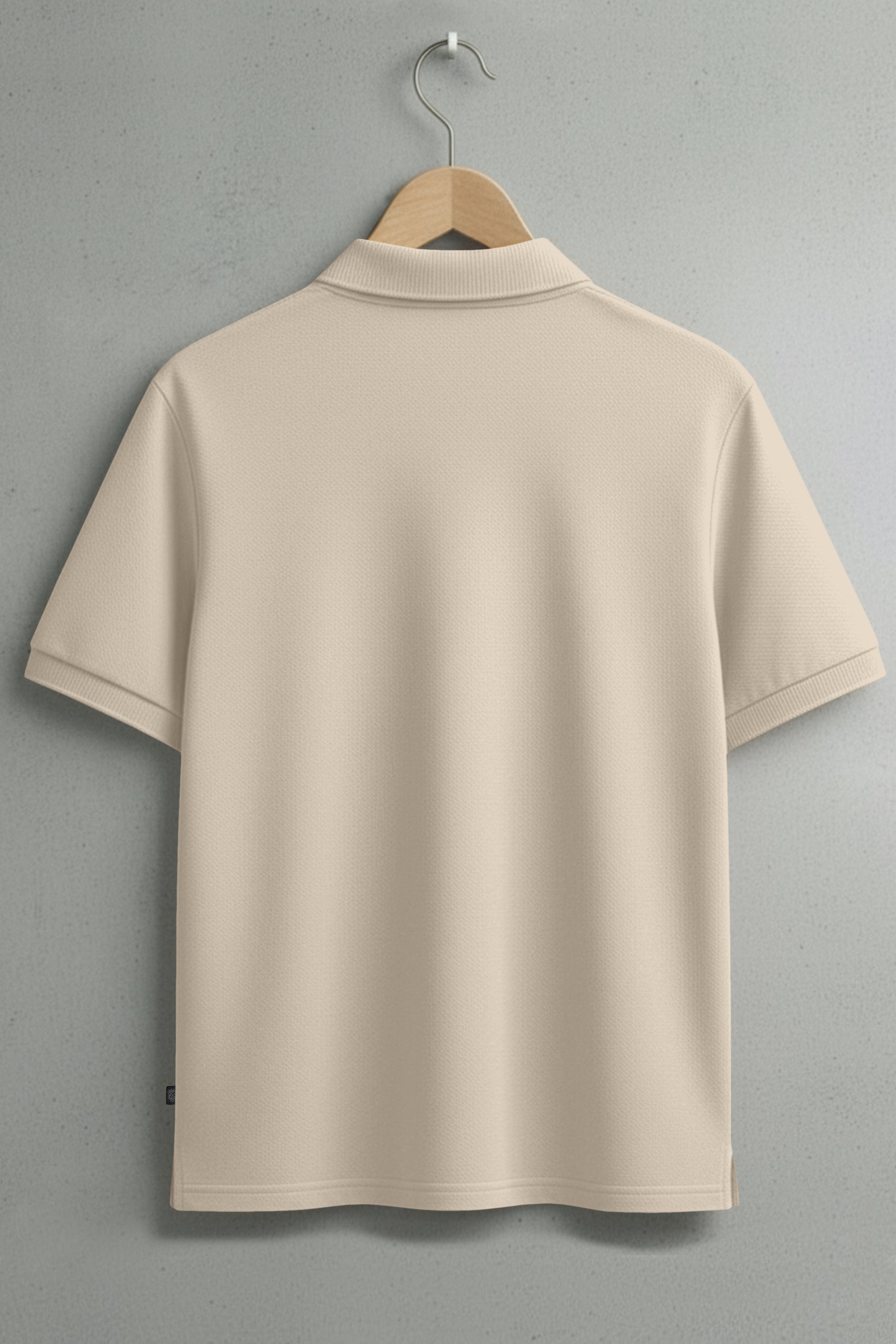 Back view of beige short-sleeve polo shirt on hanger against gray wall
