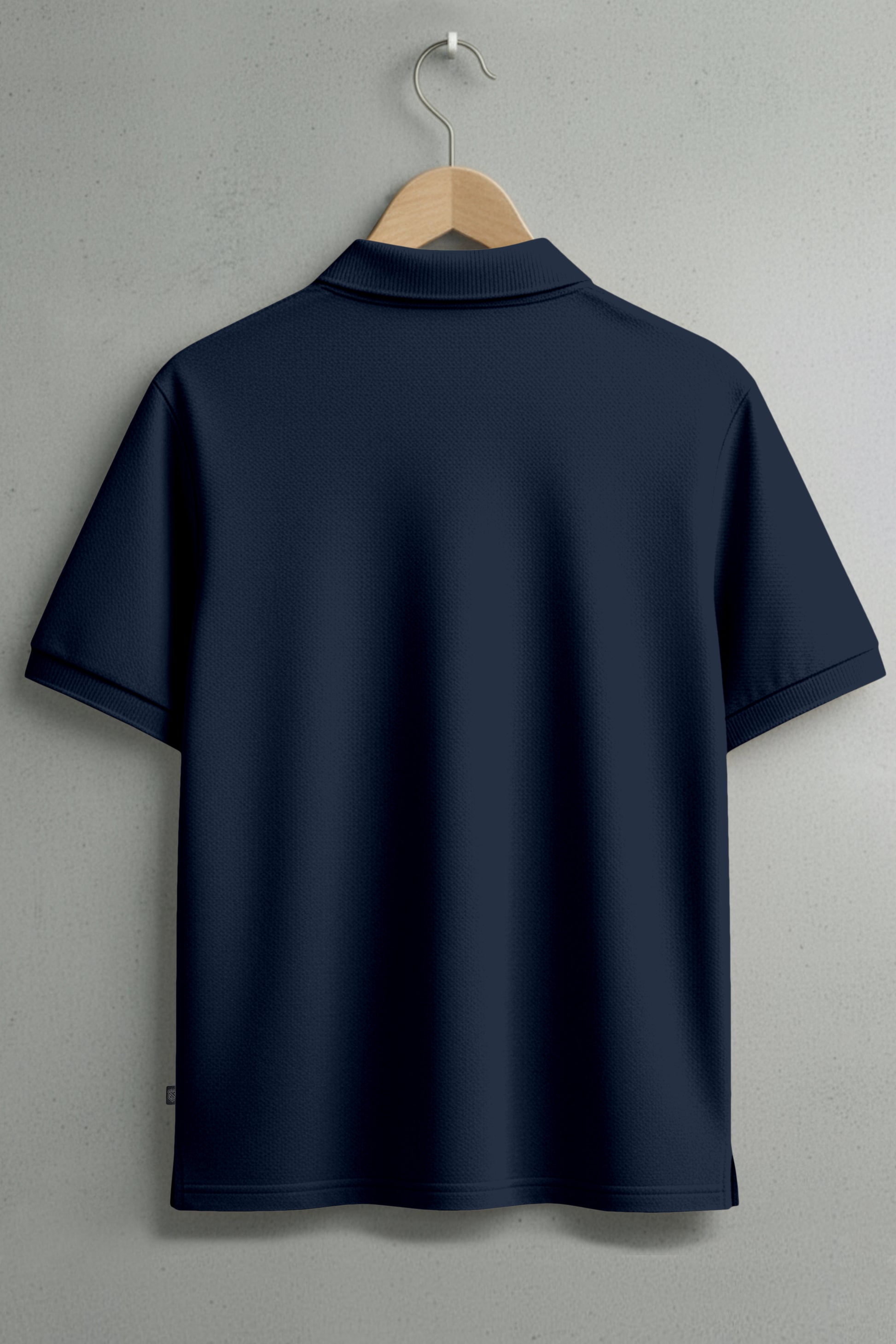 Plain navy blue short sleeve polo shirt on hanger against light wall