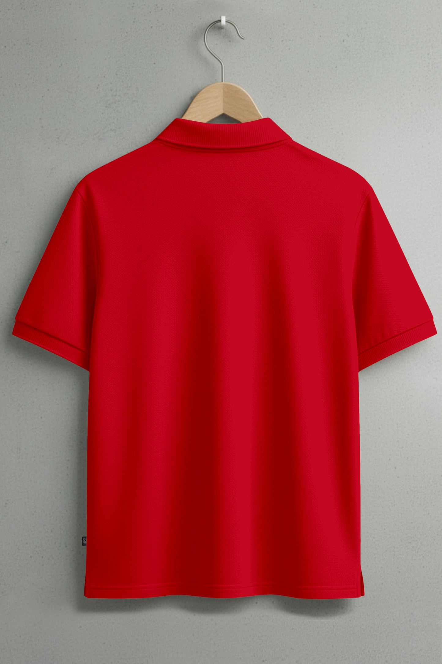 Back view of plain red short sleeve polo shirt on hanger against gray wall