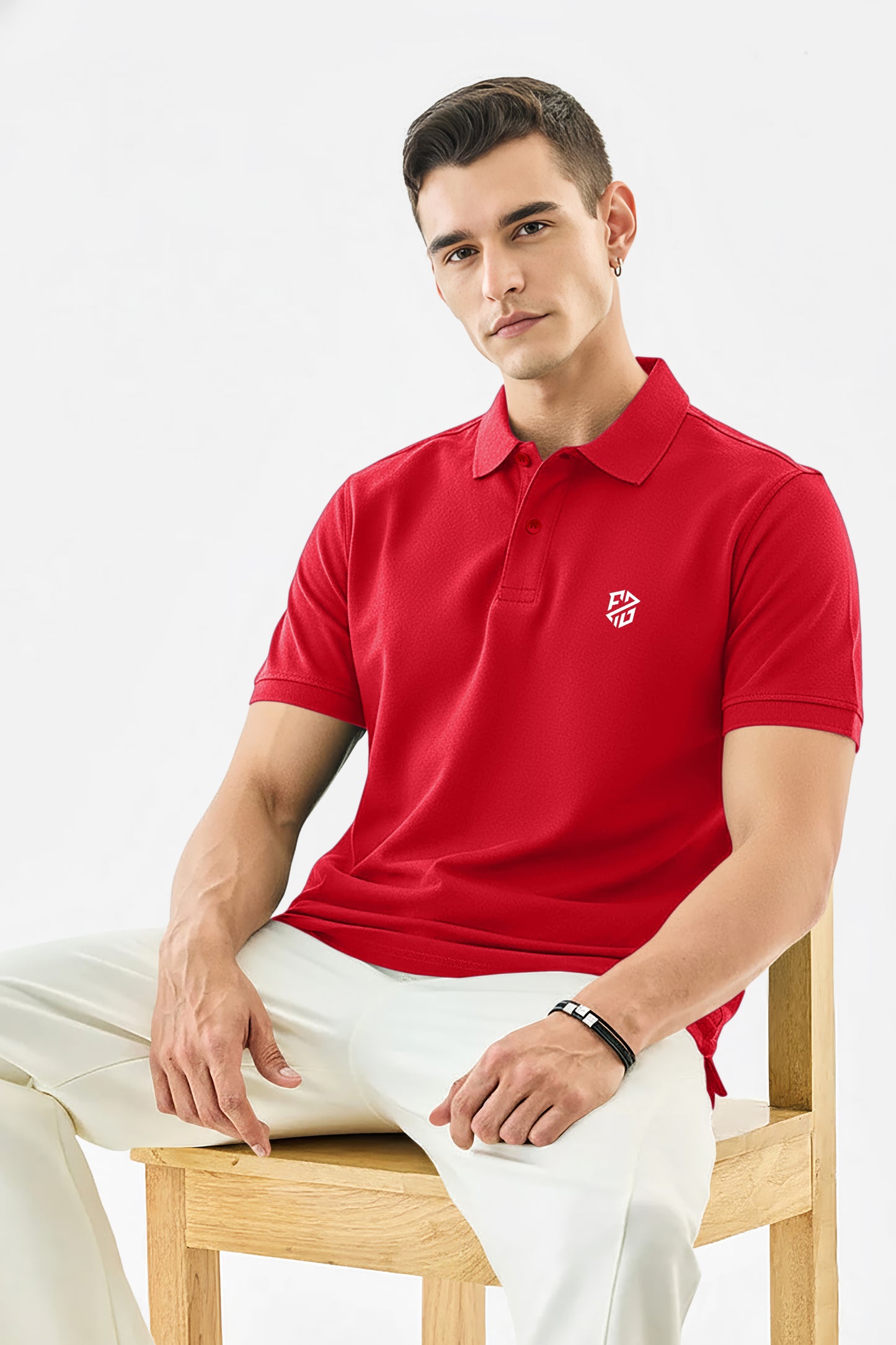 Man wearing a red polo shirt with logo and white pants sitting on a wooden chair
