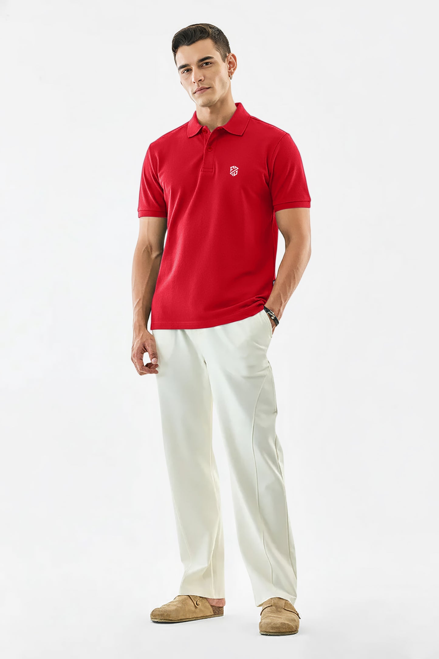 Man wearing a red polo shirt with logo, white trousers, and tan loafers on white background