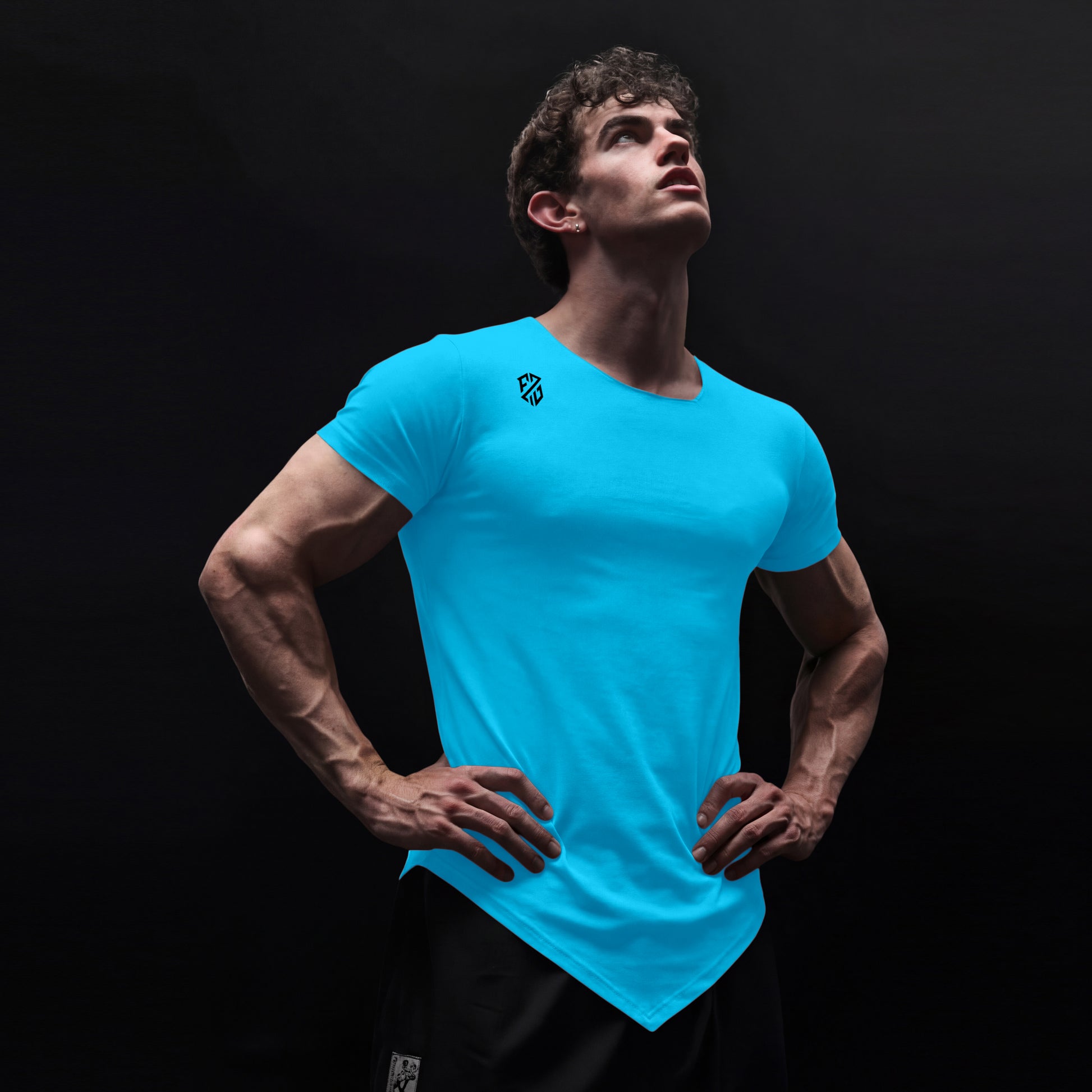 Athletic man wearing a bright blue fitted V-hem t-shirt with chest logo on black background