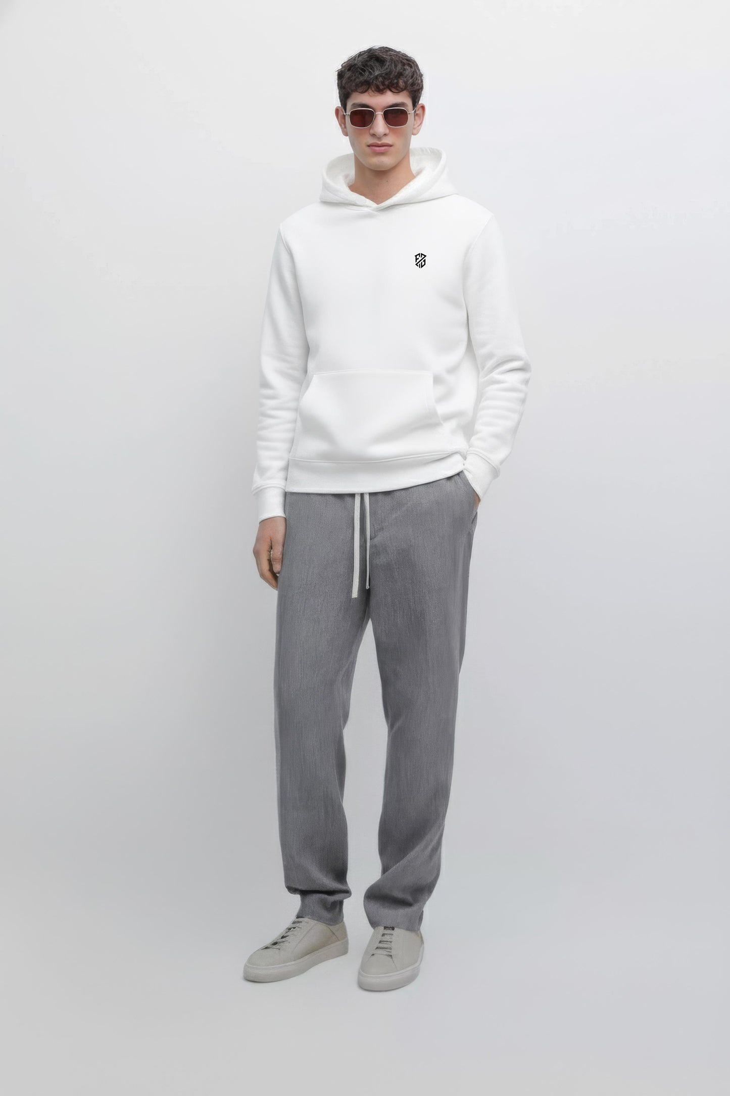 Man in white hoodie with small chest logo, gray drawstring pants, and light gray sneakers