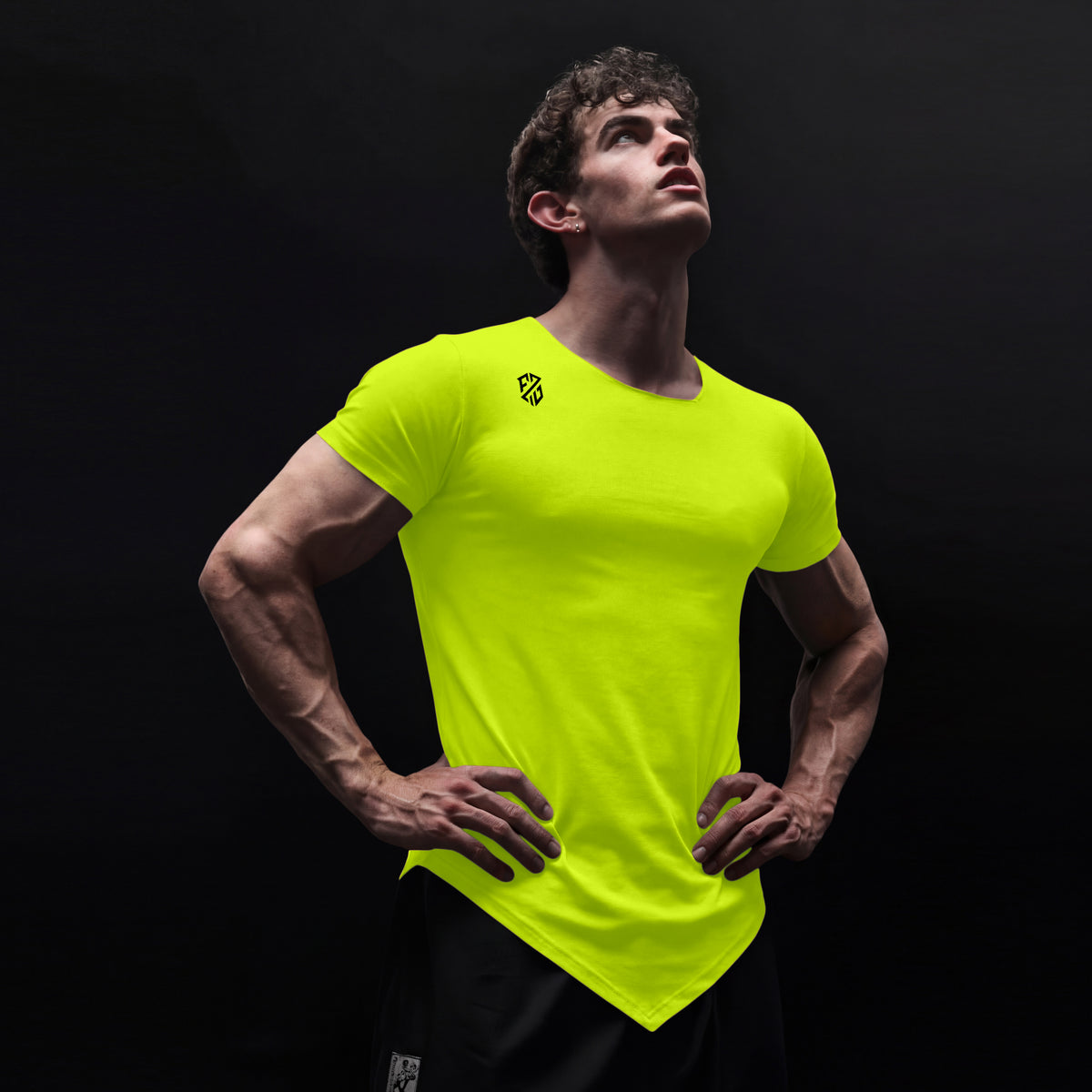 Man wearing neon yellow athletic t-shirt with logo, black shorts, black background