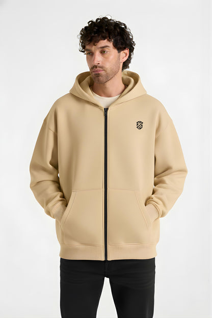 Man wearing a beige zip-up hoodie with black logo and front pockets, casual fashion
