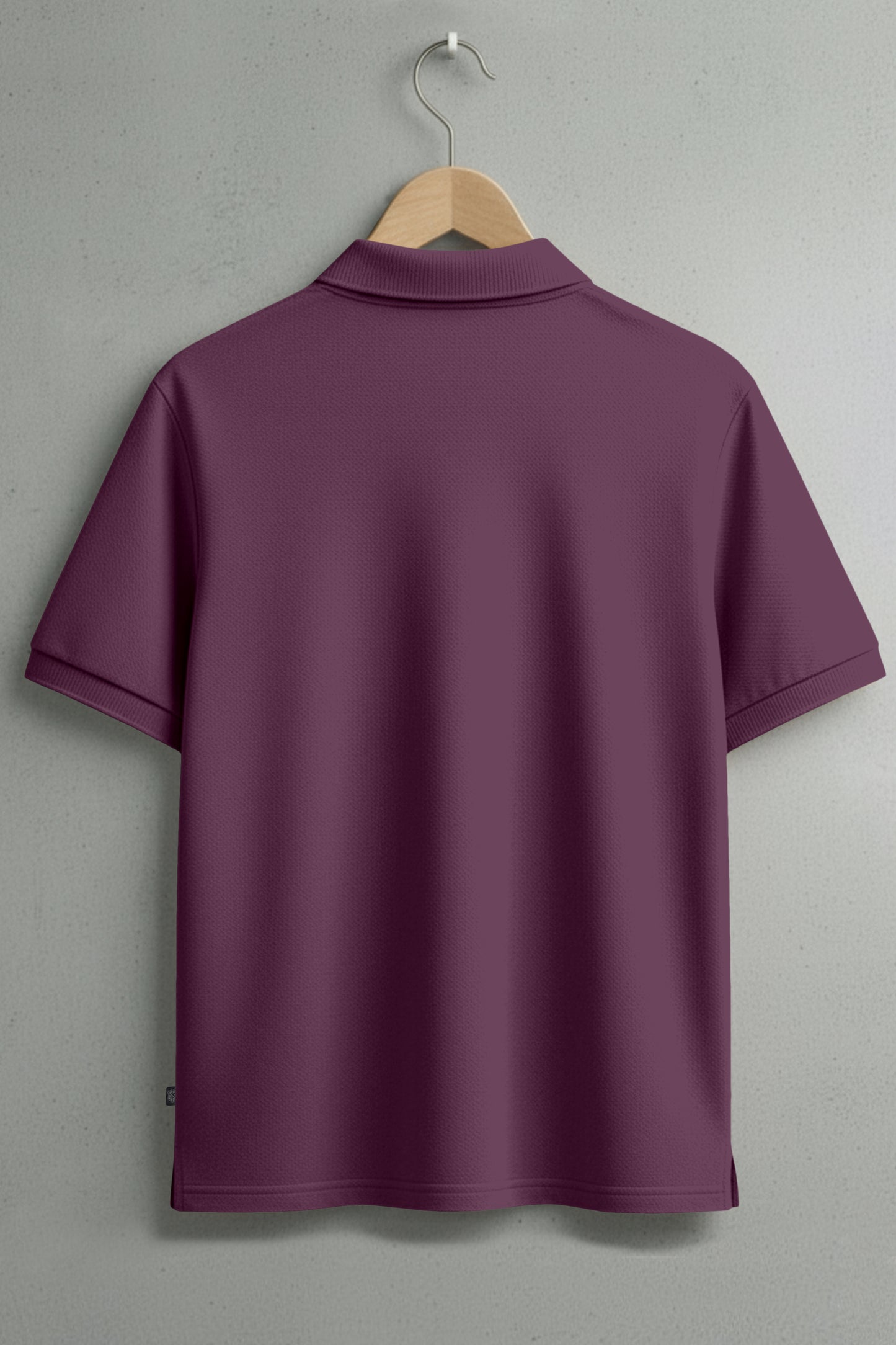 Back view of short-sleeve maroon polo shirt on hanger against gray wall