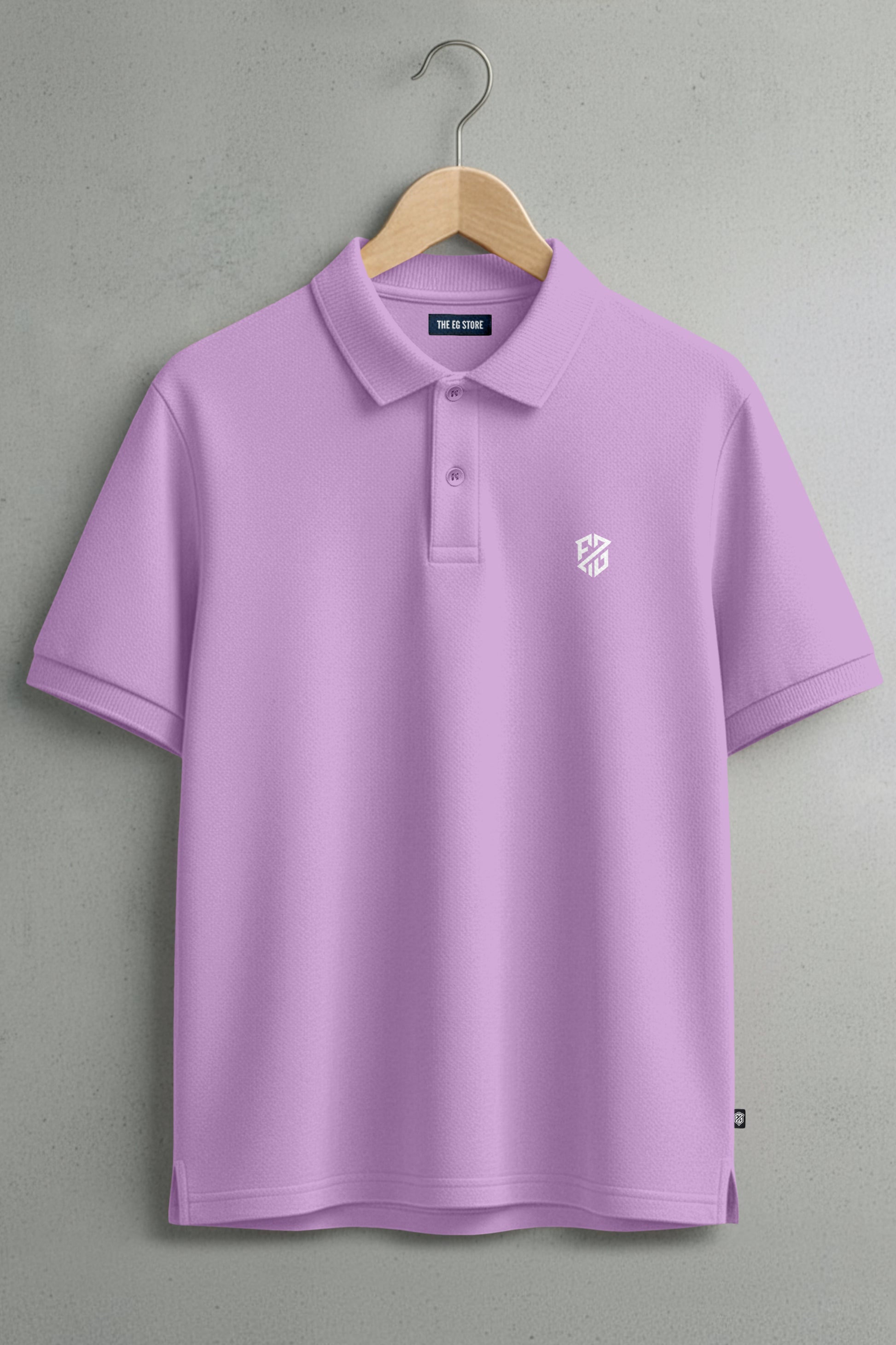Lilac short-sleeve polo shirt with white logo, hanging on wooden hanger against gray wall