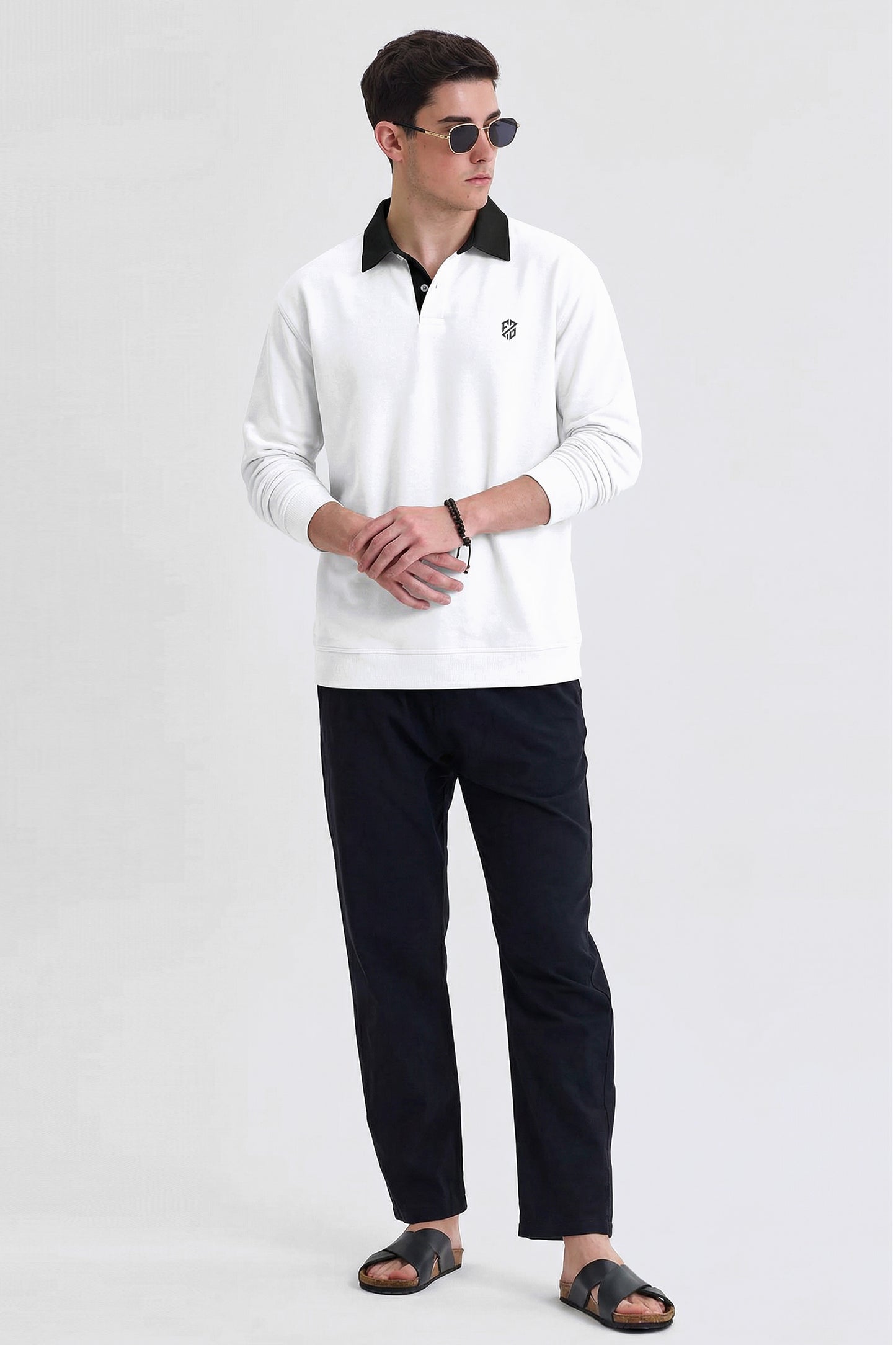 Man wearing white long-sleeve polo shirt, black pants, sandals, and sunglasses on plain background