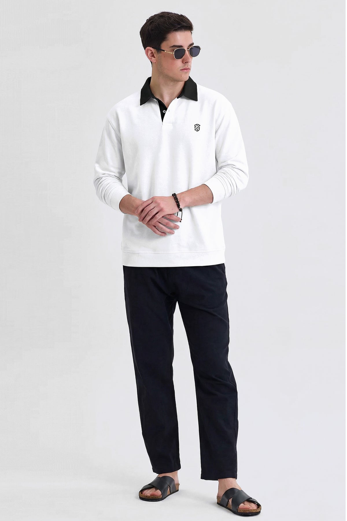 Man wearing white long-sleeve polo shirt, black pants, sandals, and sunglasses on plain background